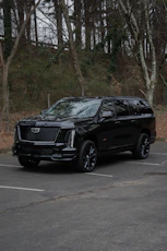 A black cadillac escalade parked in a lot.