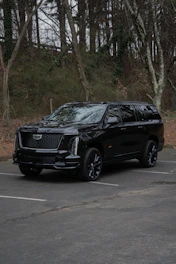 A black cadillac escalade parked in a lot.