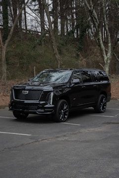 A black cadillac escalade parked in a lot.