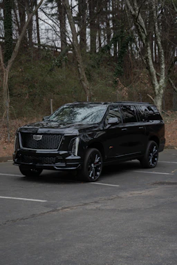 A black cadillac escalade parked in a lot.