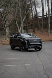 A black cadillac escalade parked in a lot.