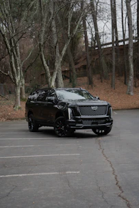A black cadillac escalade parked in a lot.