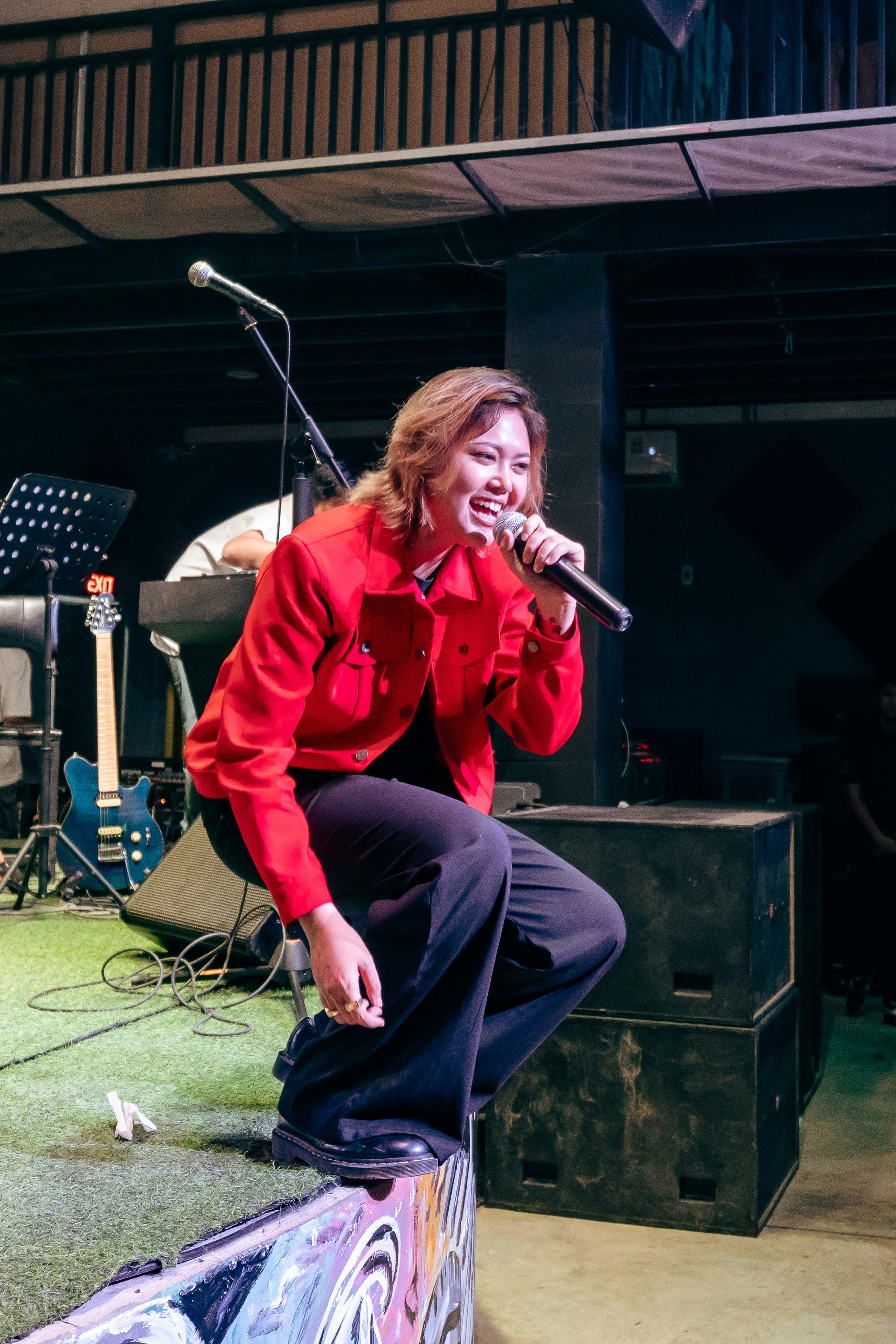Una mujer con chaqueta roja cantando a un micrófono.