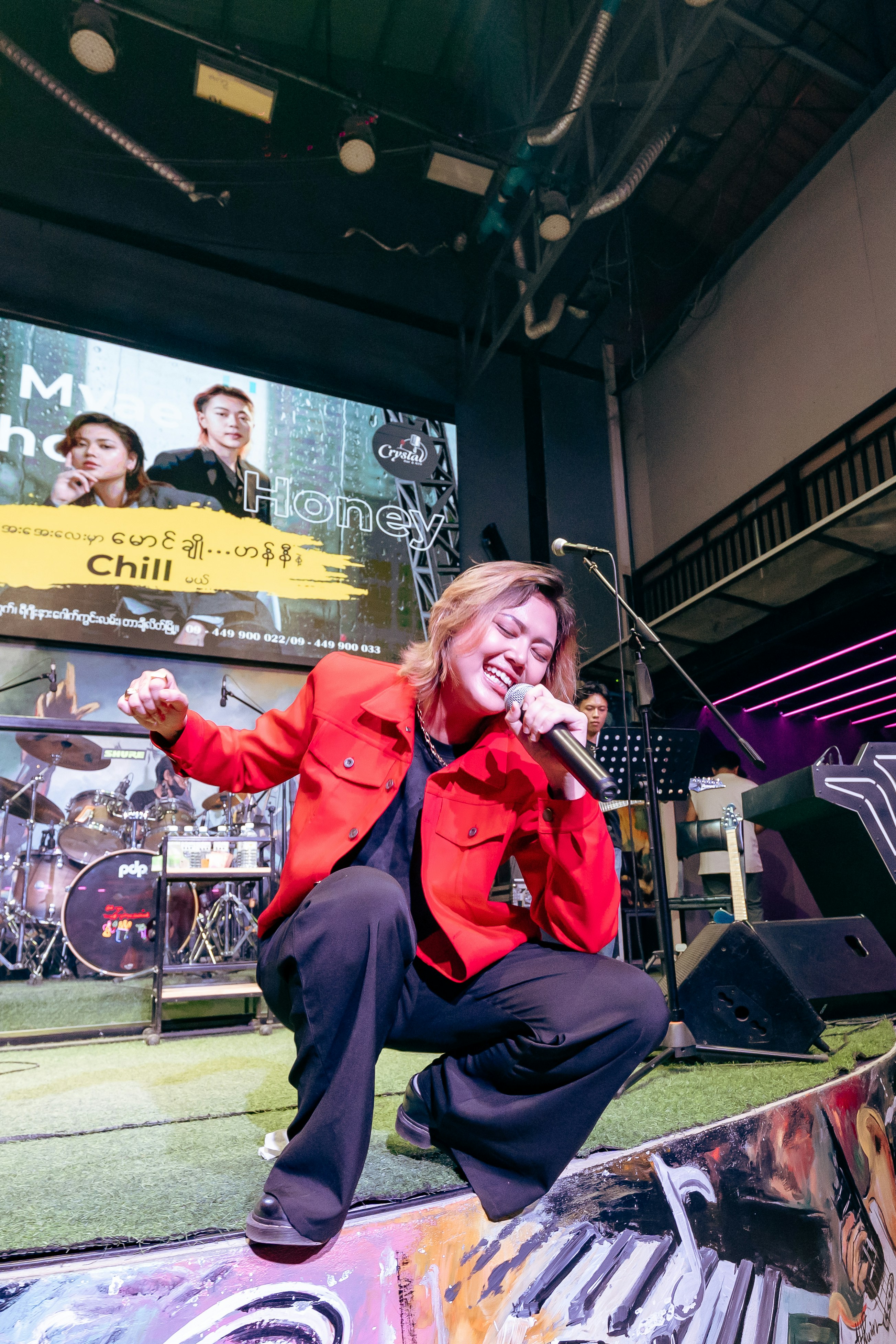 Cantante actuando en el escenario con la banda de fondo.