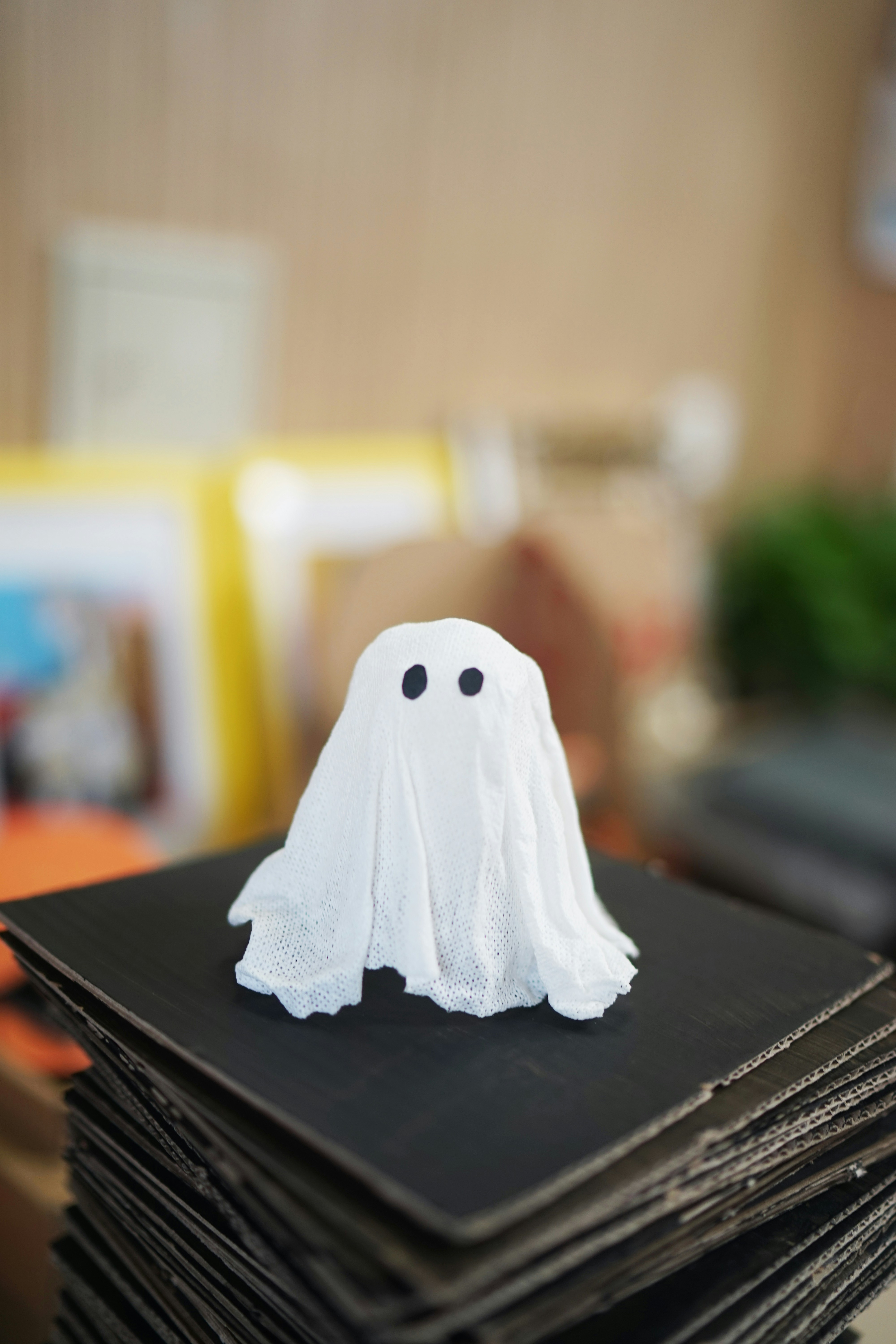 A small ghost decoration on a stack of black cardboard.