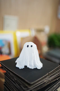 A small ghost decoration on a stack of black cardboard.