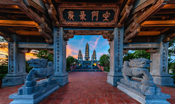 Ancient pagodas viewed through a stone archway at sunset