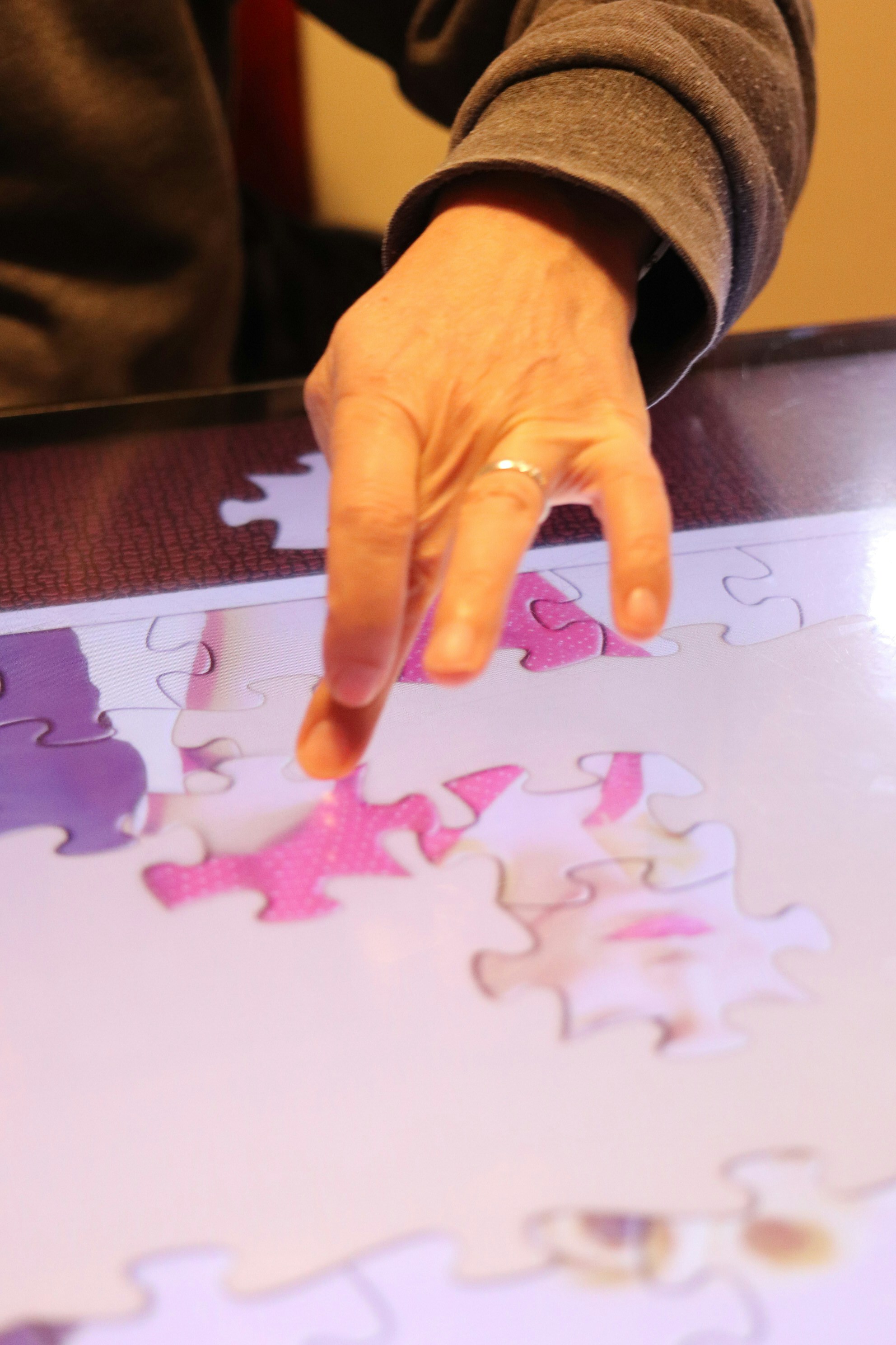 Person's hand placing puzzle piece on digital screen.