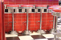 A row of chrome stools along a tiled counter, photographed before opening