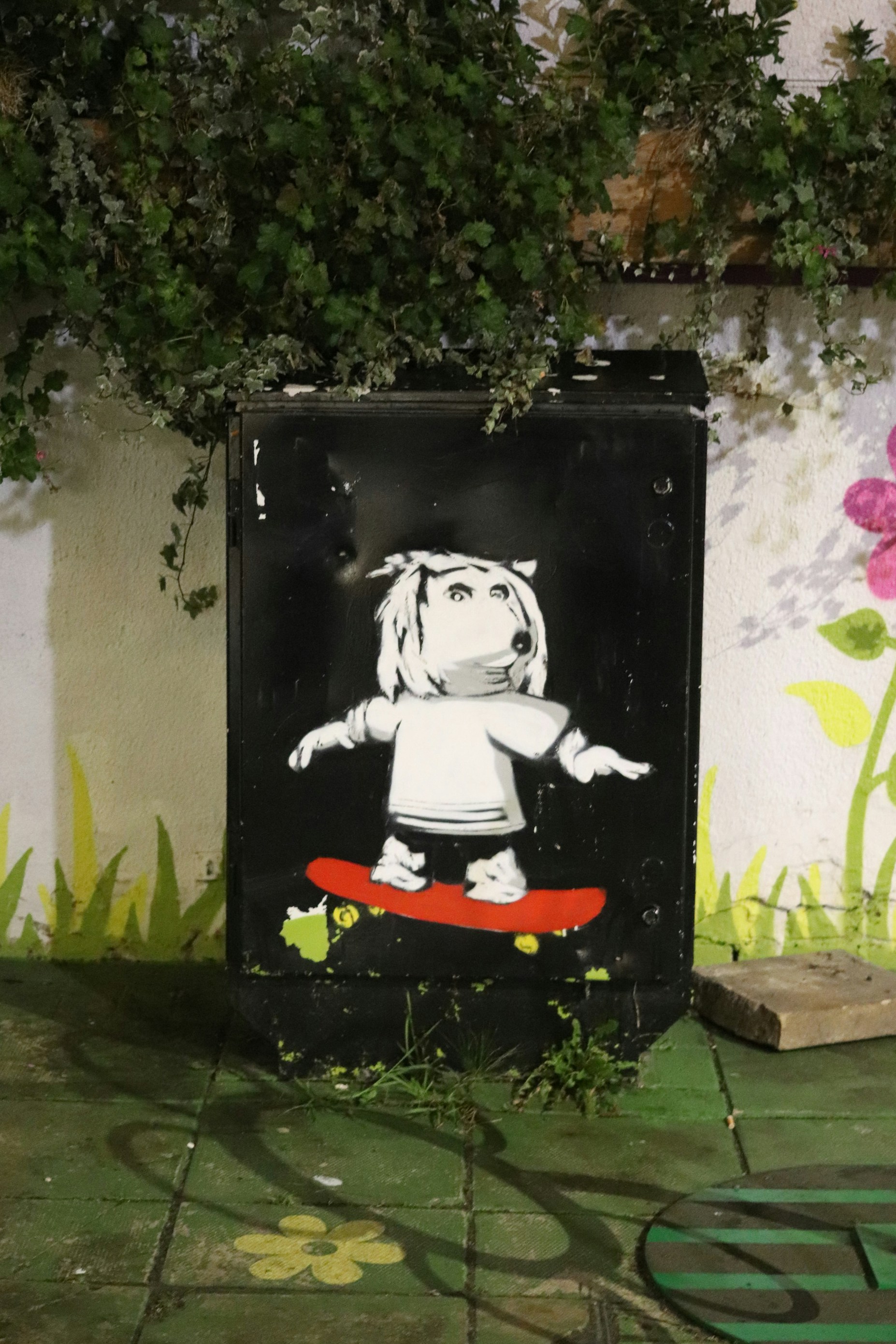 Graffiti of a dog on a skateboard on a wall.