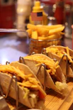Three tacos with shredded cheese and fries