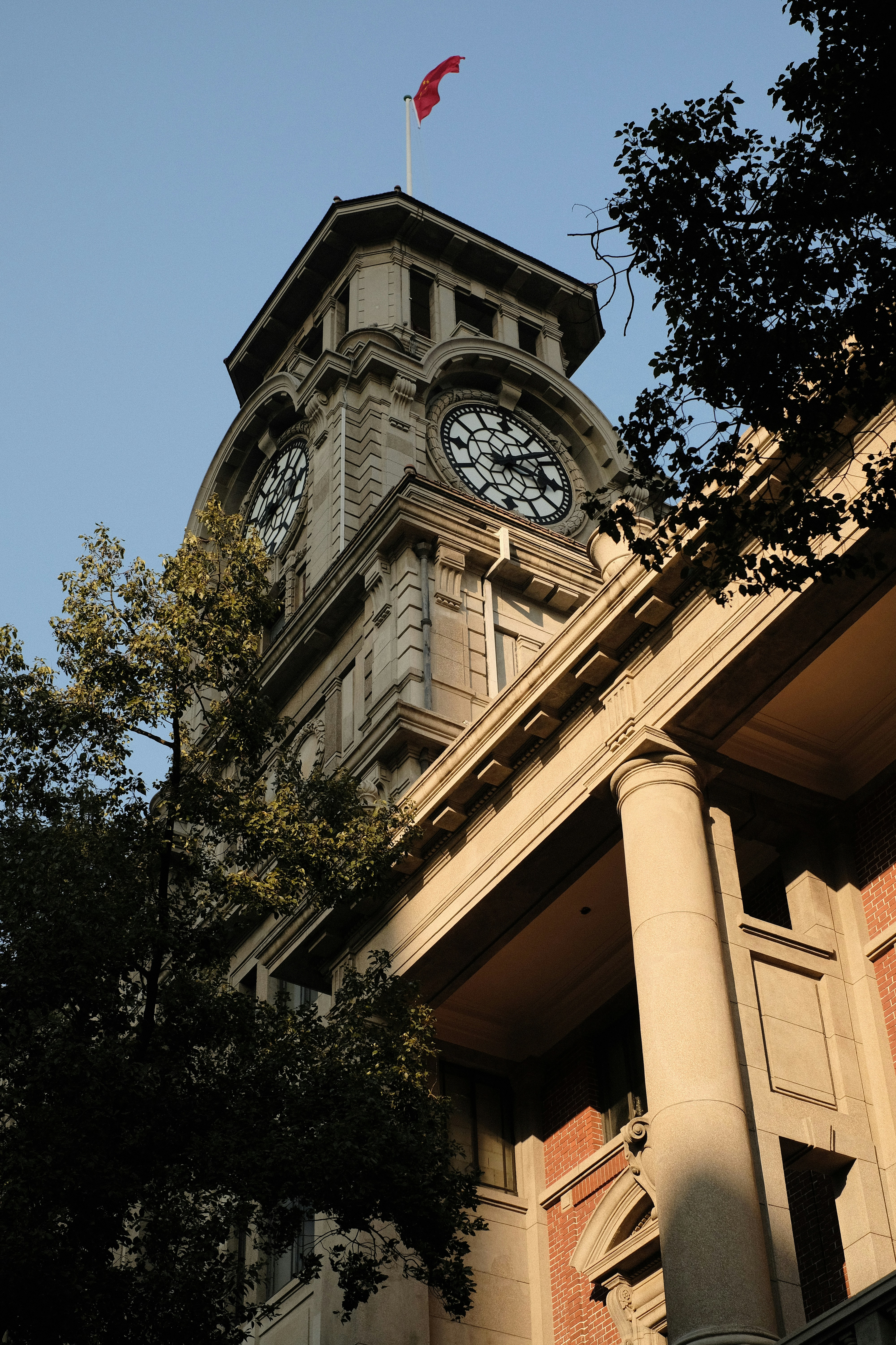 A historic clock tower with a red flag