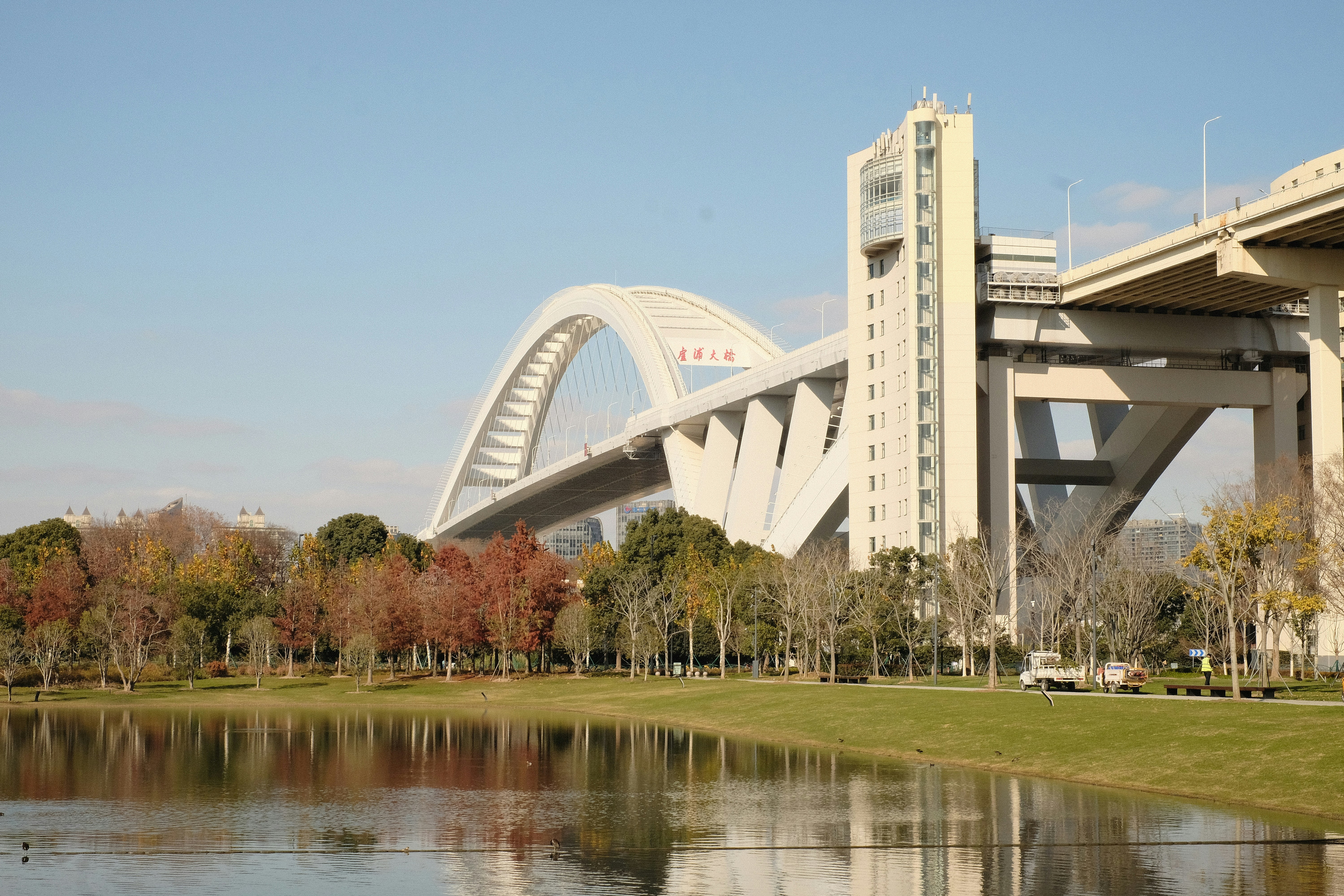 Modern bridge arching over a calm body of water.