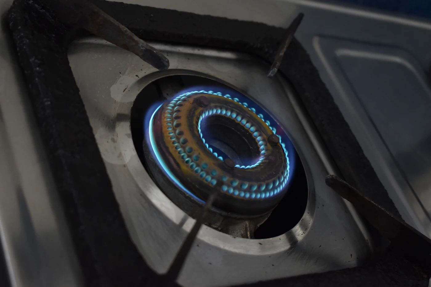 Close-up of a gas stove burner with a steady blue flame