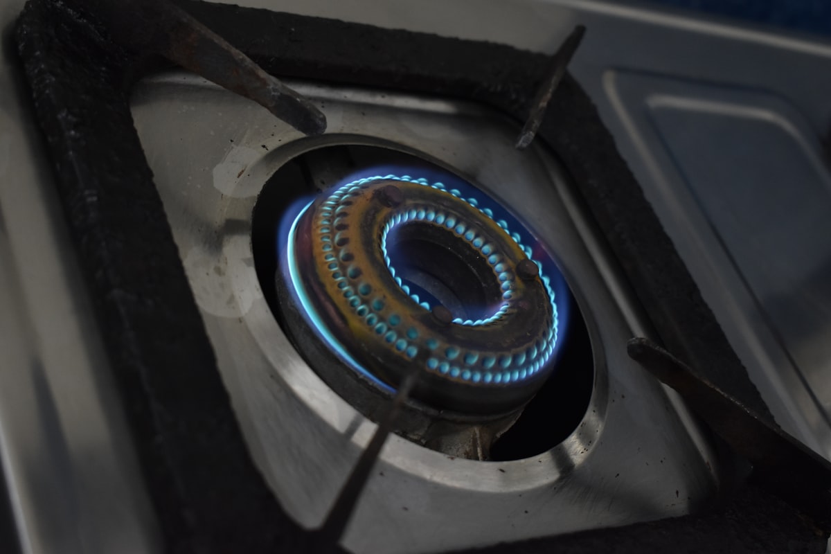 Close-up of a gas stove burner with a bright blue natural gas flame