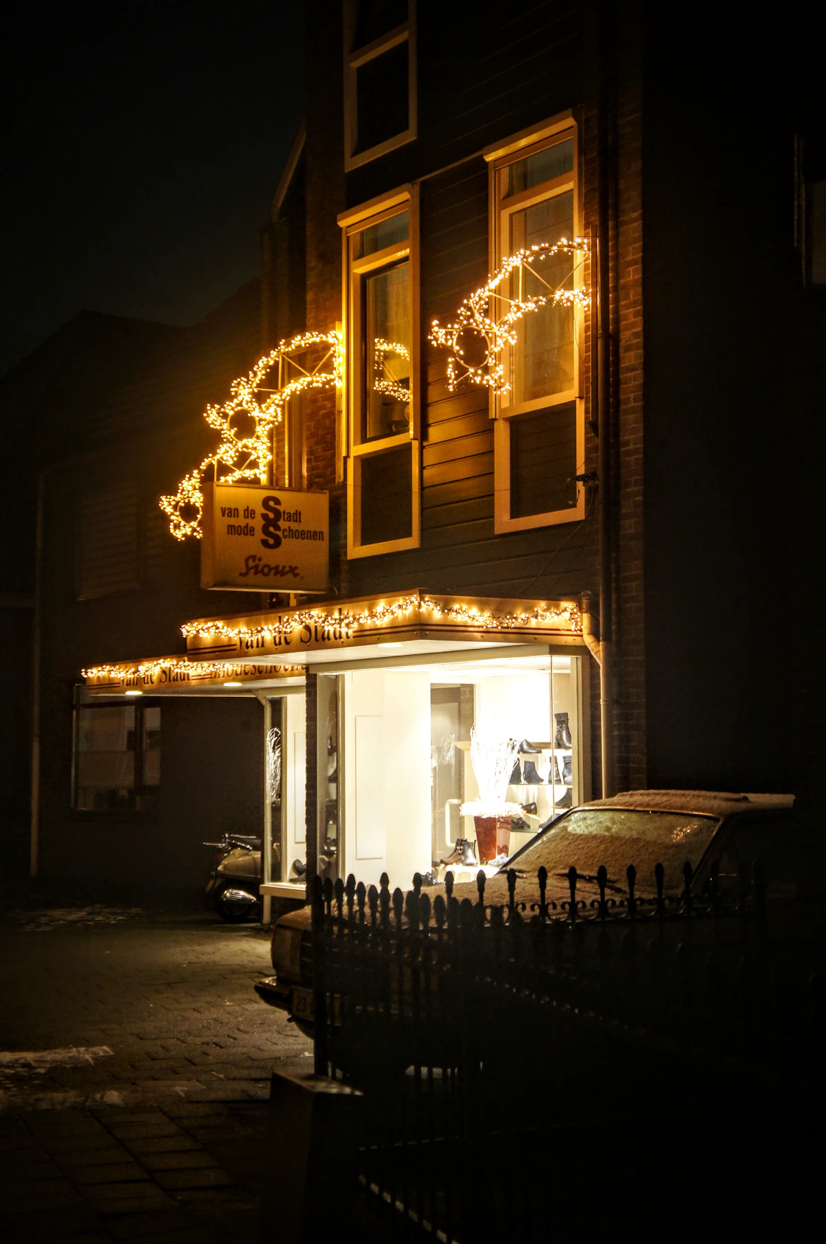 Storefront facade outlined in warm string lights at night