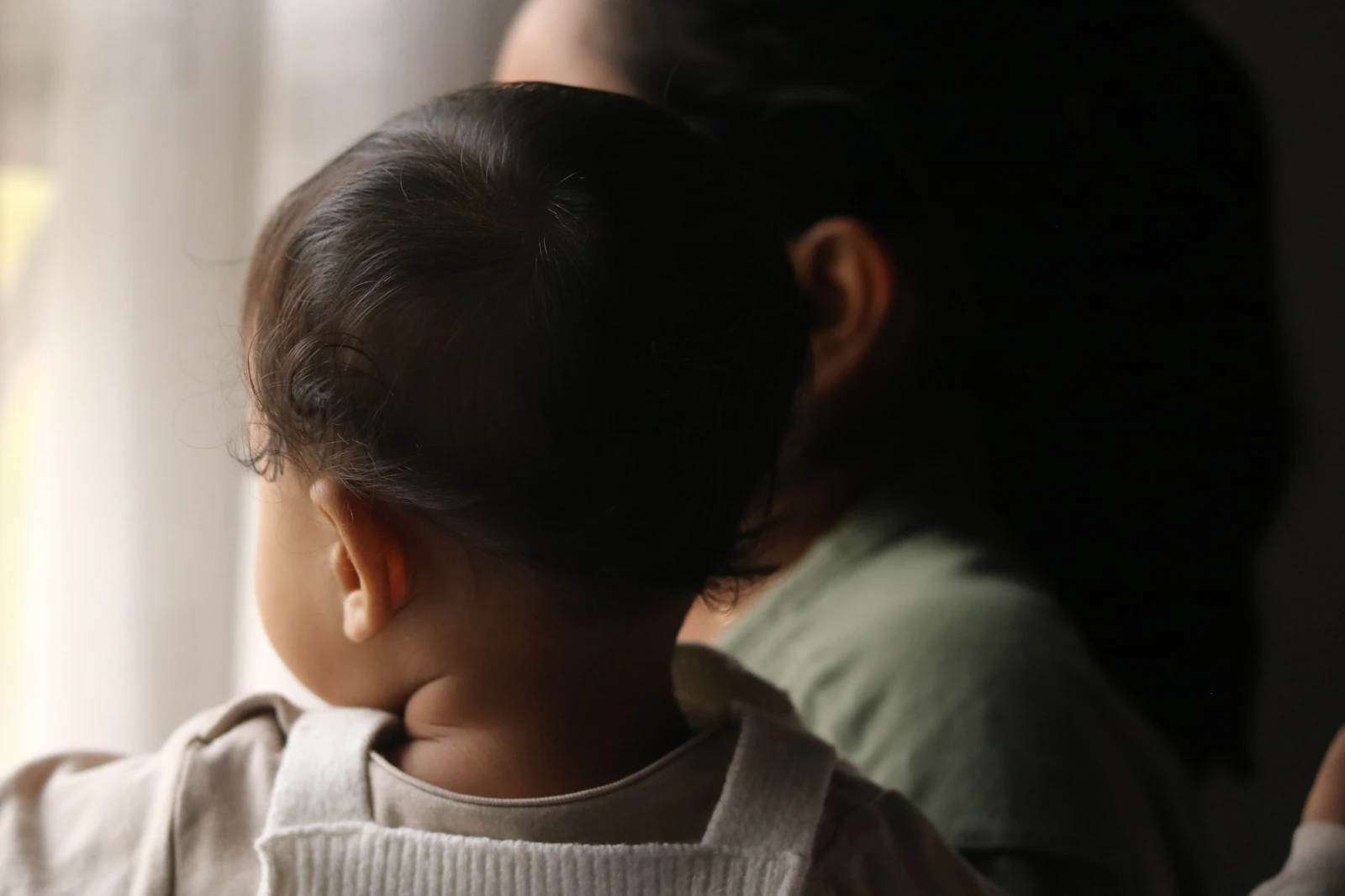 Mãe e bebê olhando pela janela em um momento silencioso no período pós-parto