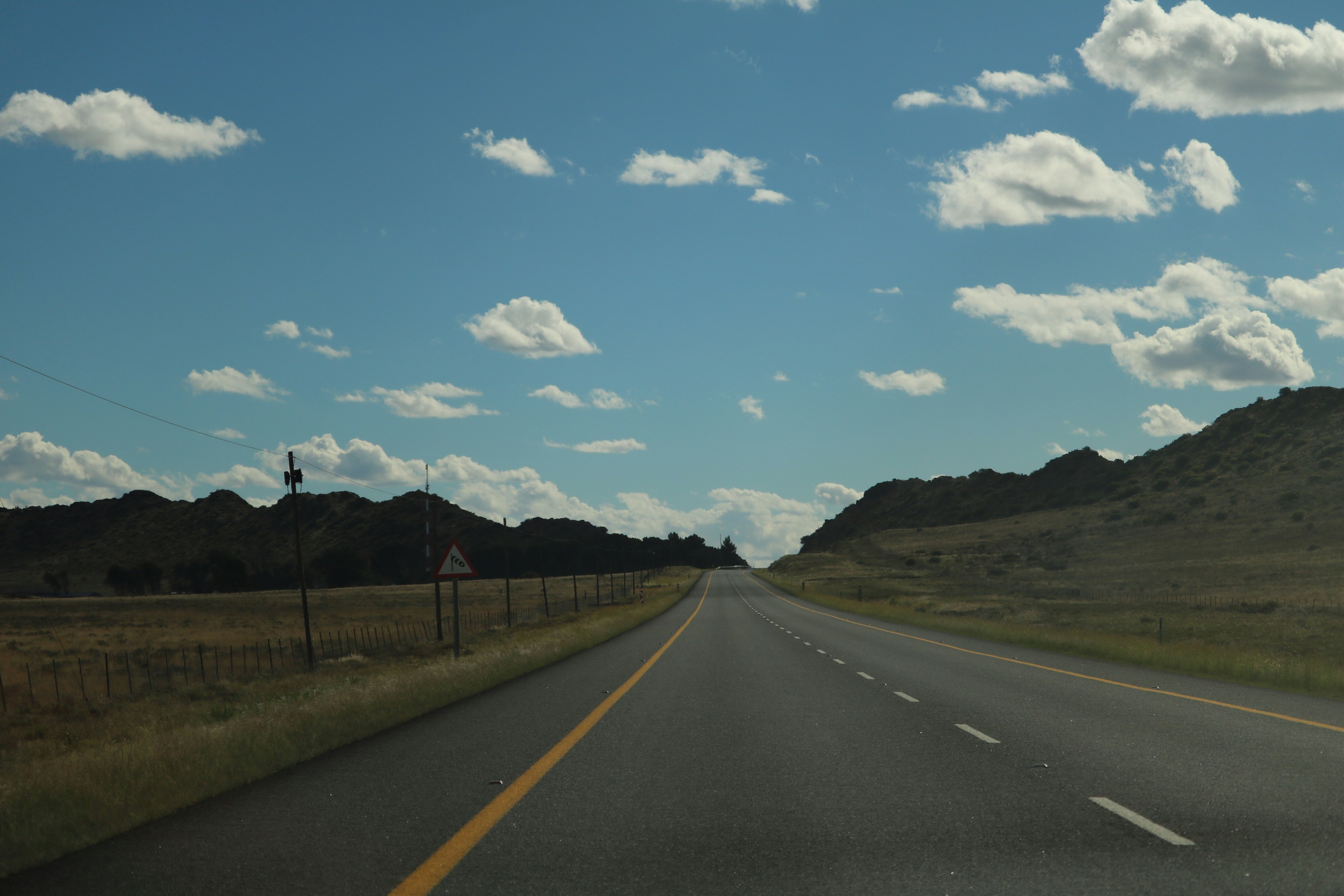 Open highway stretching towards distant hills under a cloudy sky.