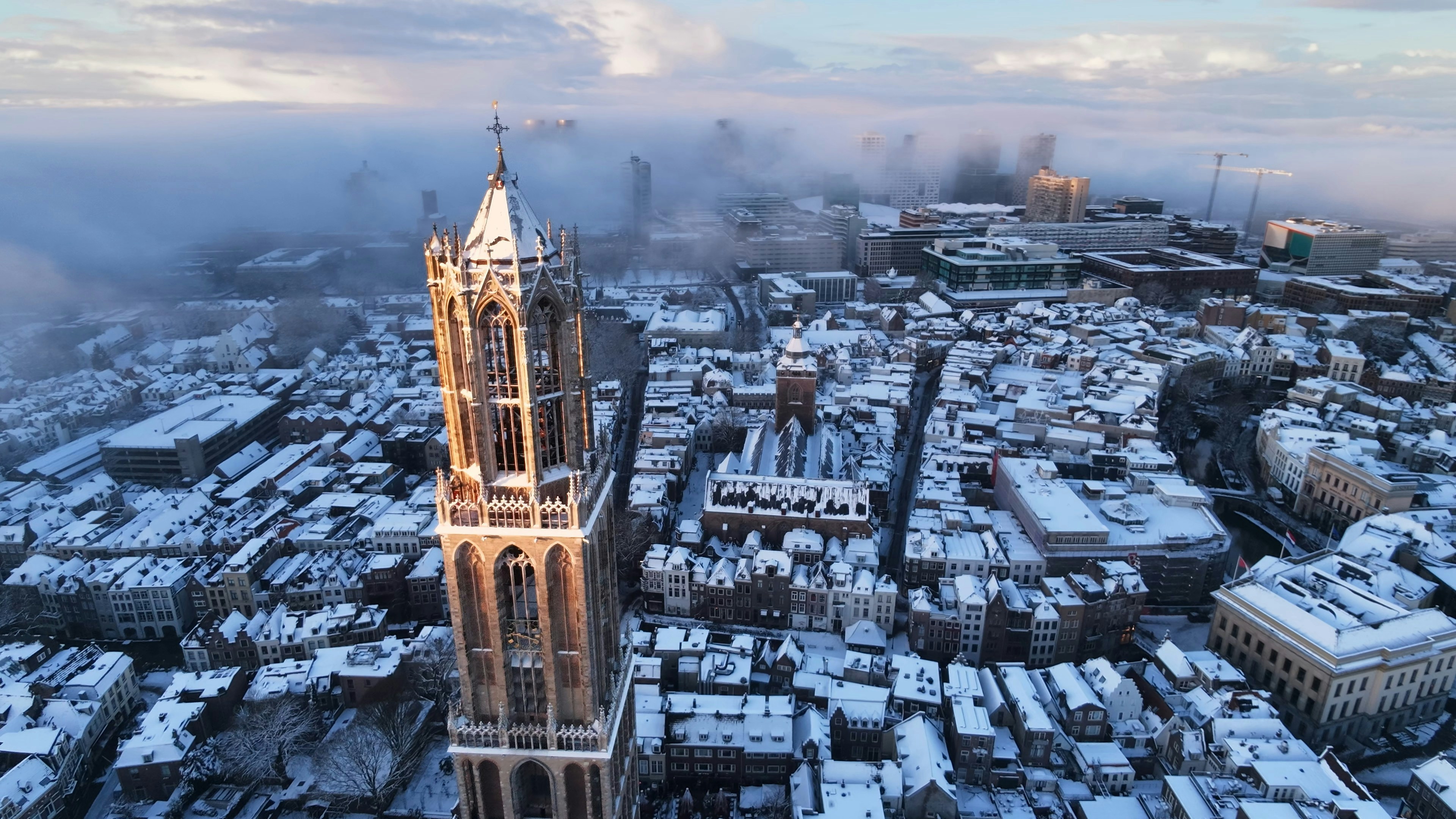 Snow-covered city with a prominent church tower.