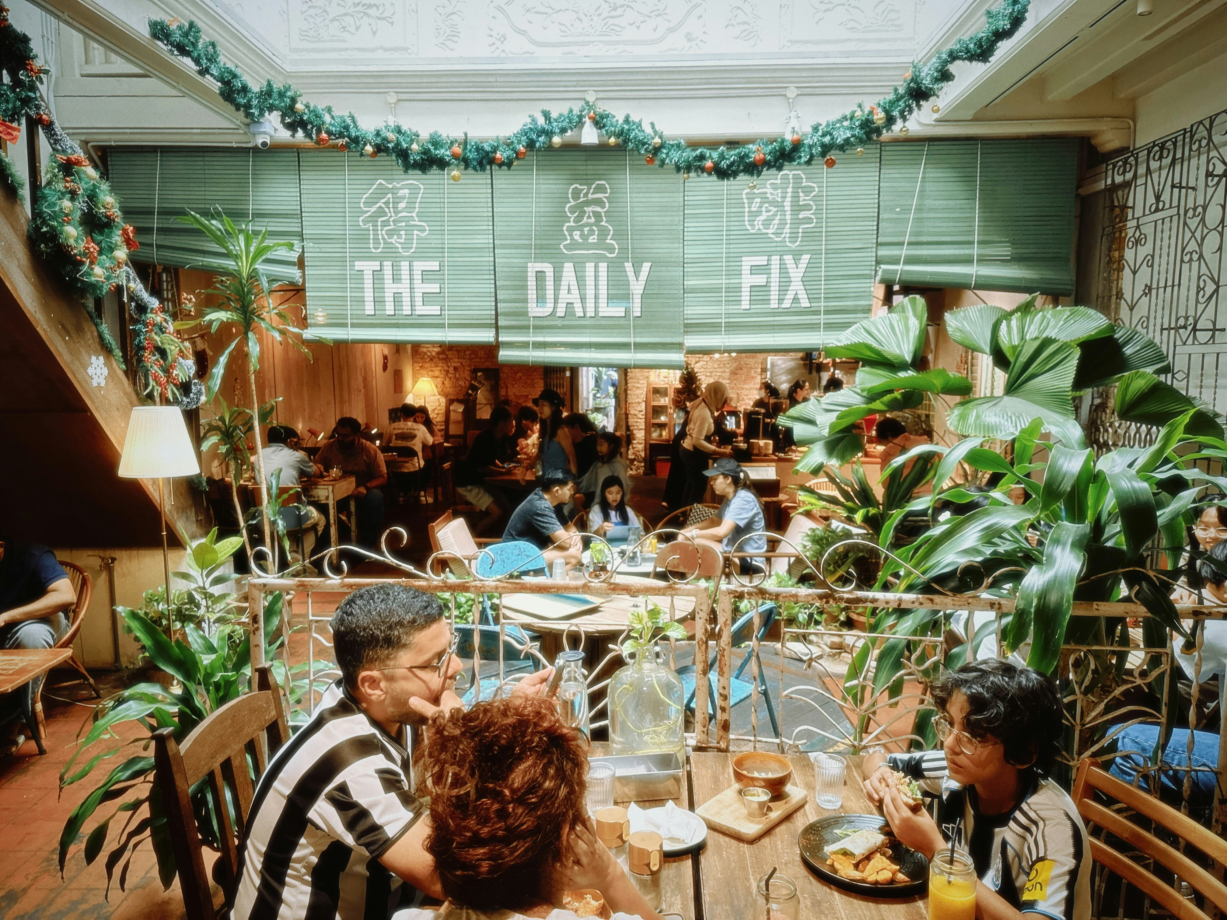 People dining inside a bustling cafe with green decor.