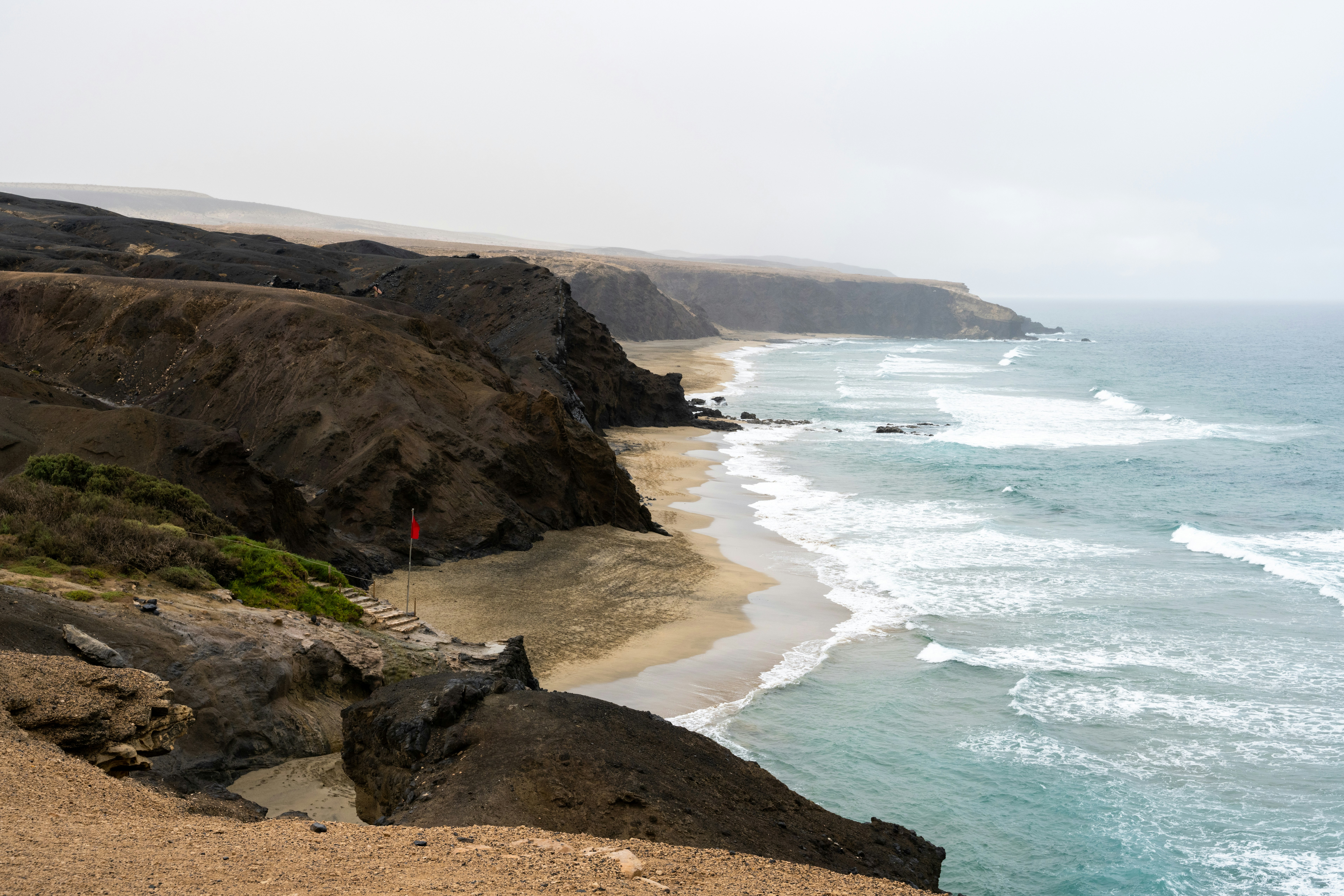 Zerklüftete Küste mit Wellen, die am Strand schlagen.