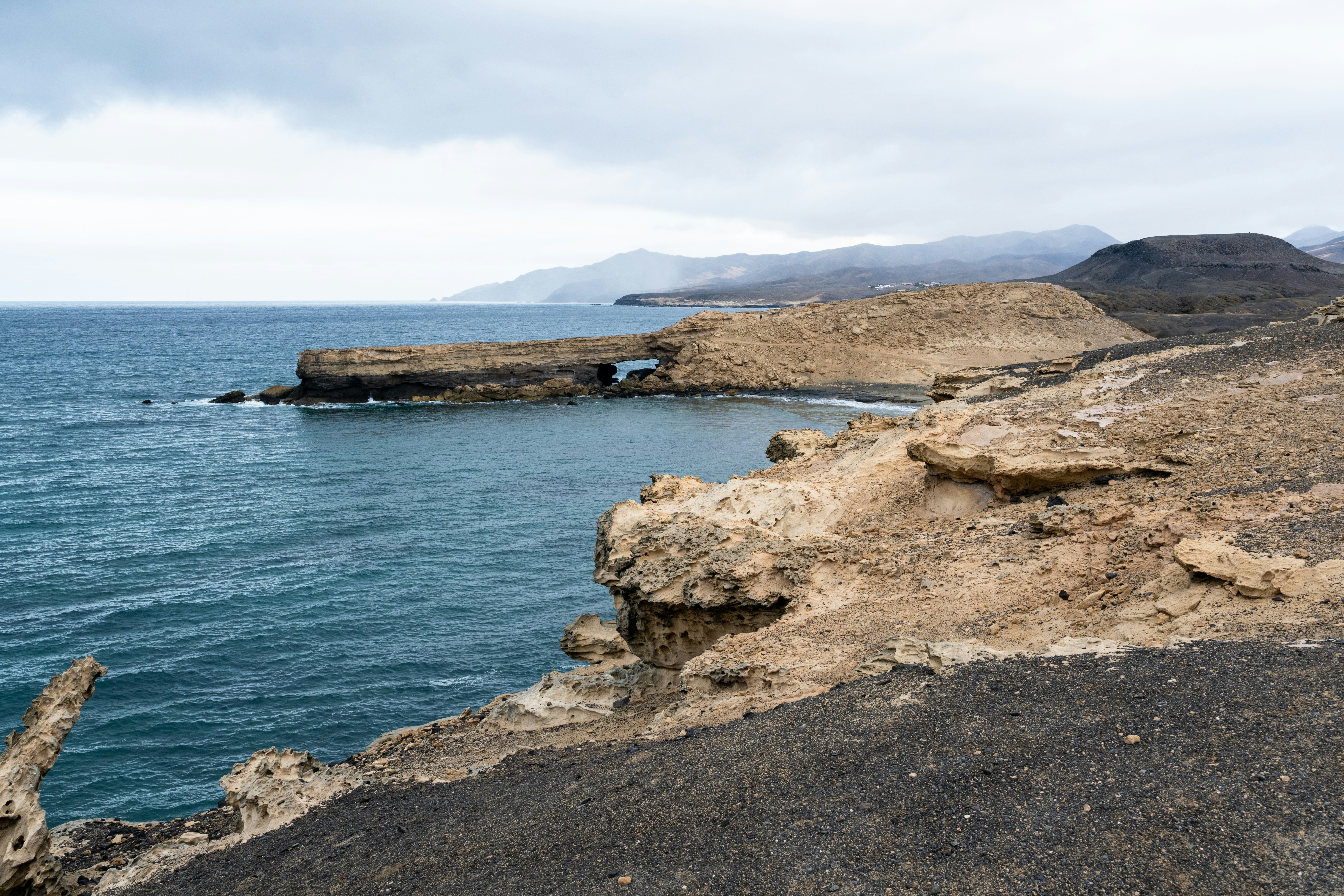 Felsige Küste mit Wellen, die gegen Klippen schlagen.
