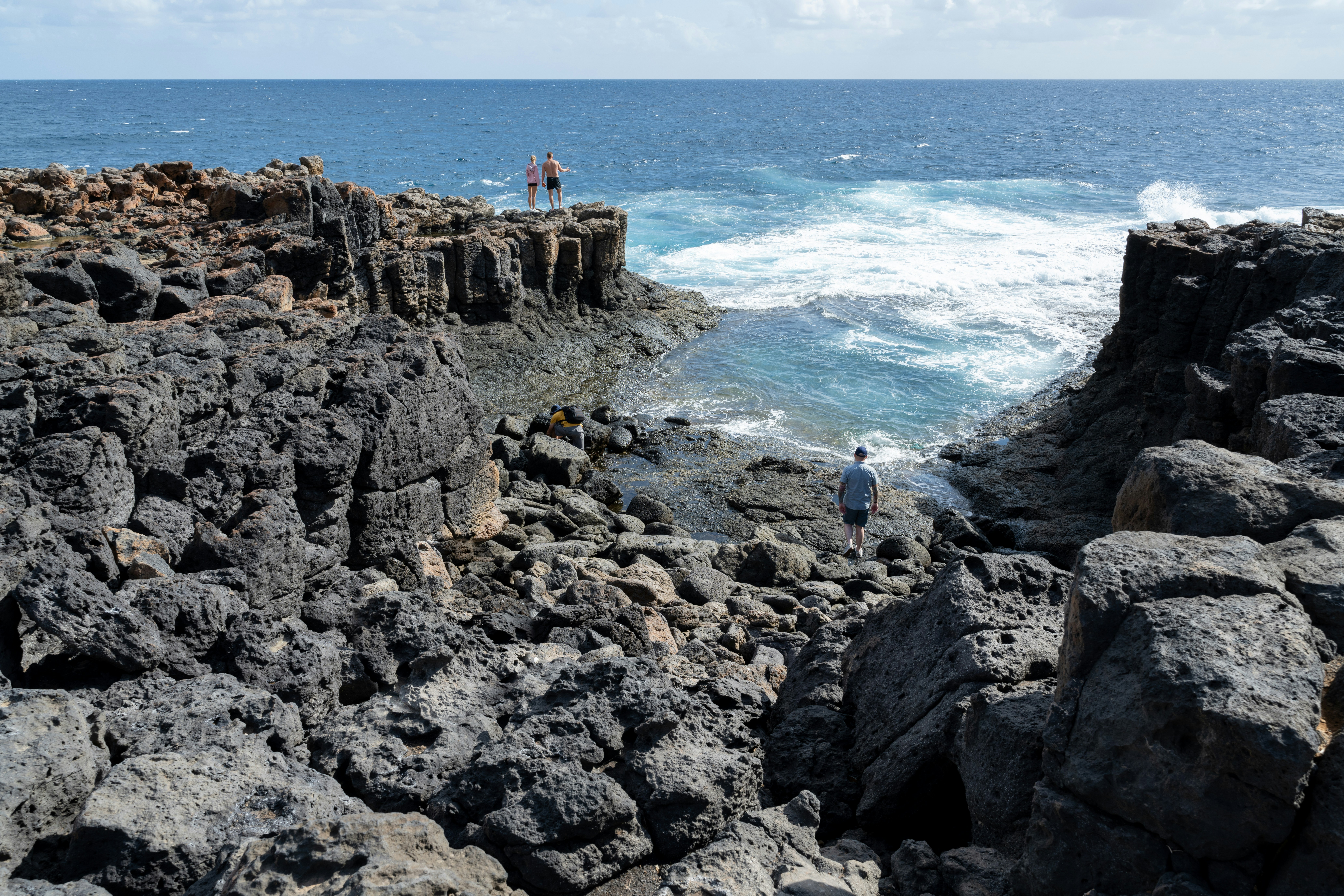 Menschen an der felsigen Küste nahe brechenden Wellen des Ozeans