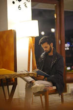 Man sitting and reading a book indoors.