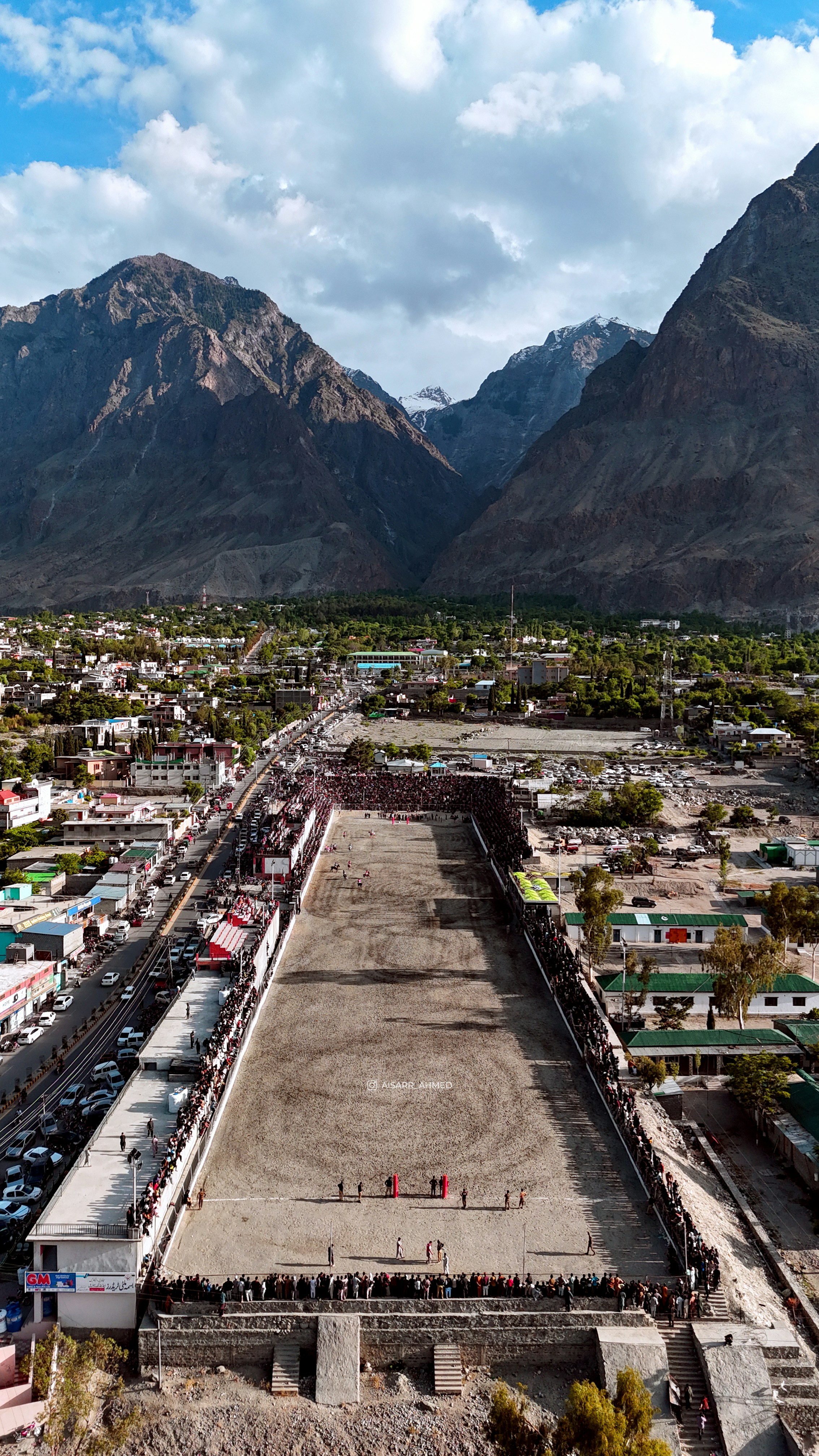 Aerial view of a polo field with spectators and mountains