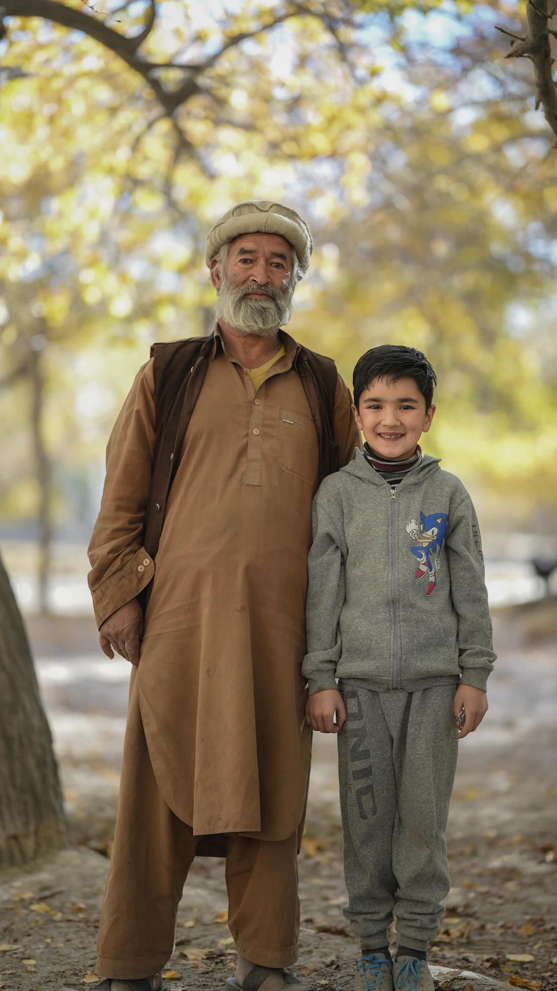 An older man and his grandson outdoors on a bright, breezy day