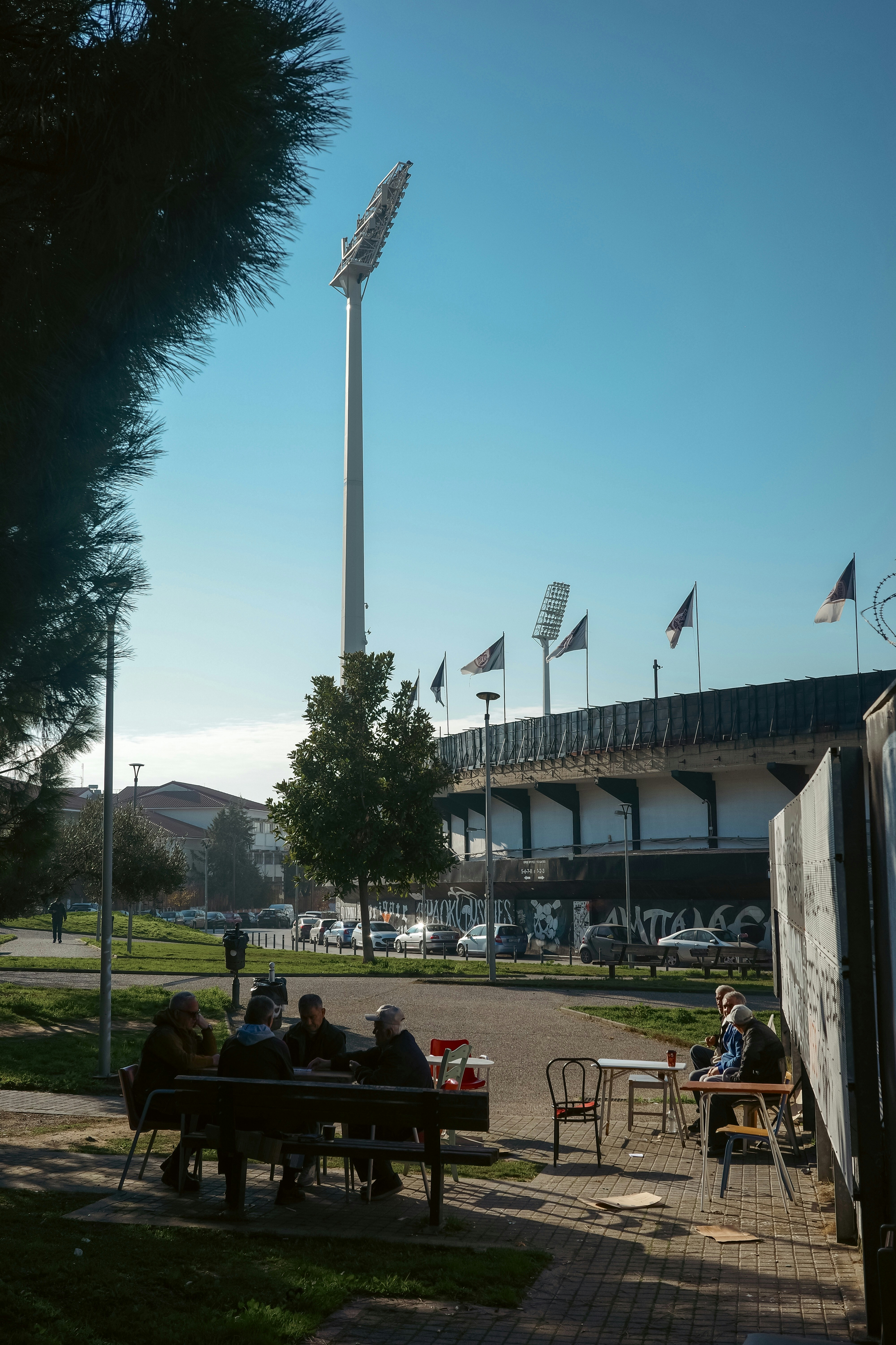 People gathered at tables outside stadium under stadium lights