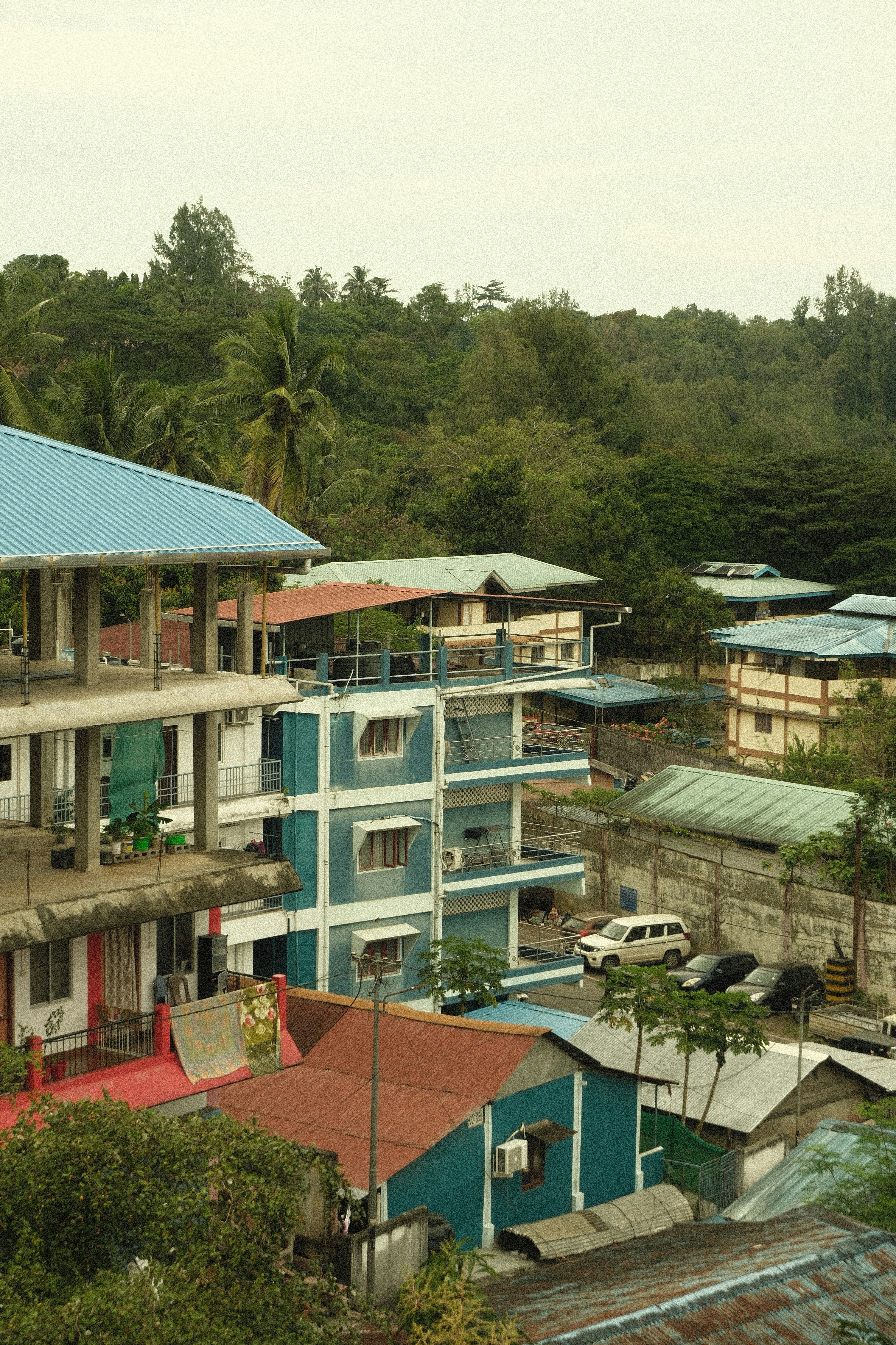 Buildings nestled among lush green trees and hills.