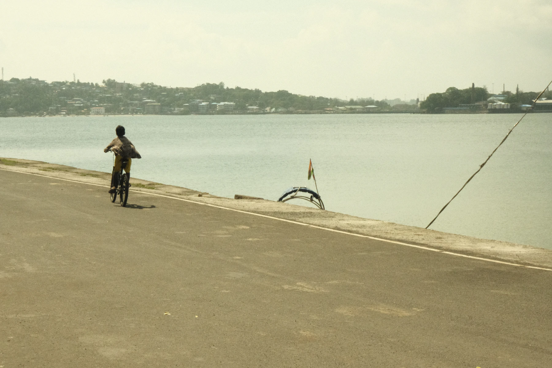 Cyclist riding along a road beside calm water in the Andaman and Nicobar Islands