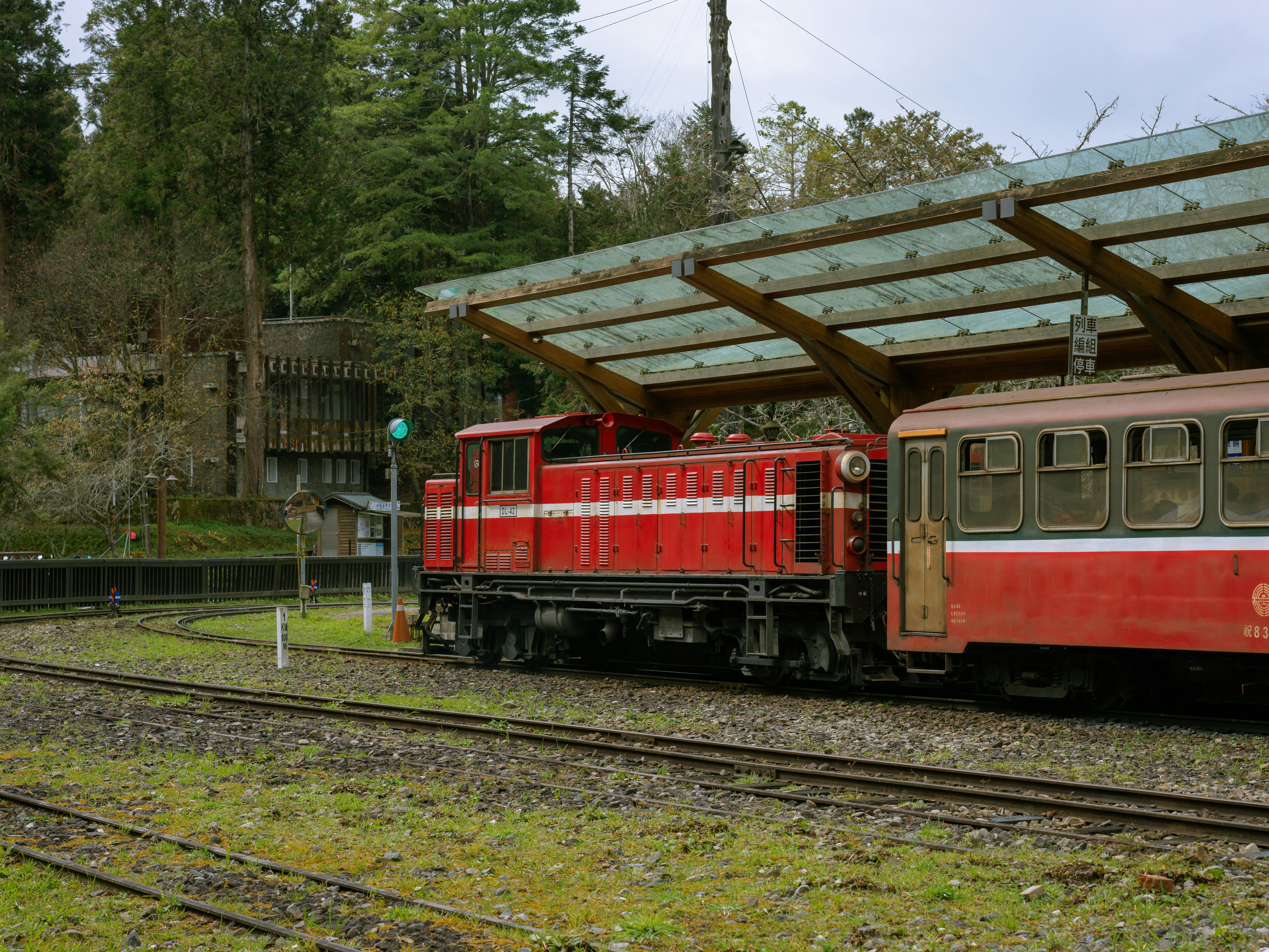 Red train engine and carriage at a station.
