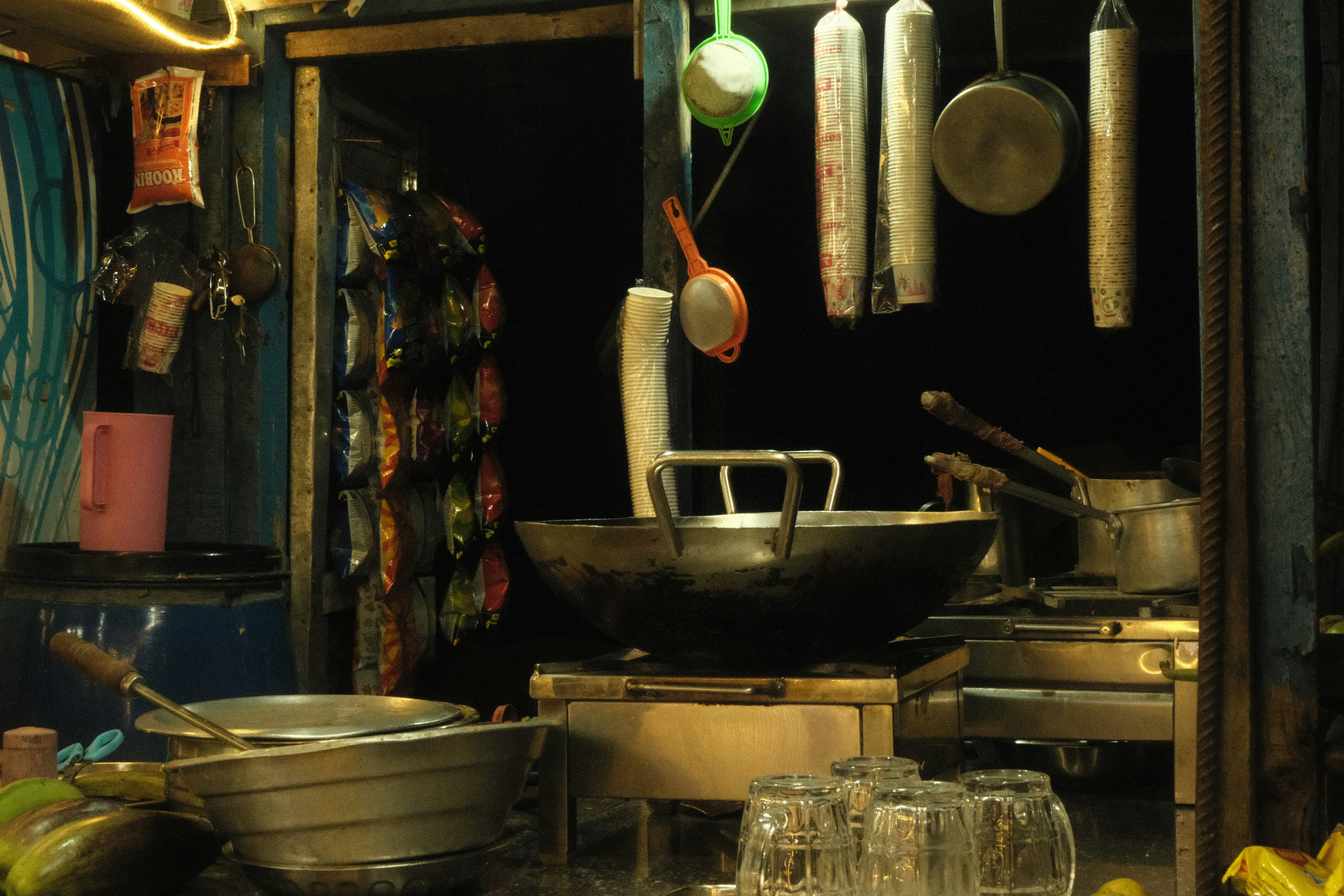 A dimly lit food stall with cooking utensils.
