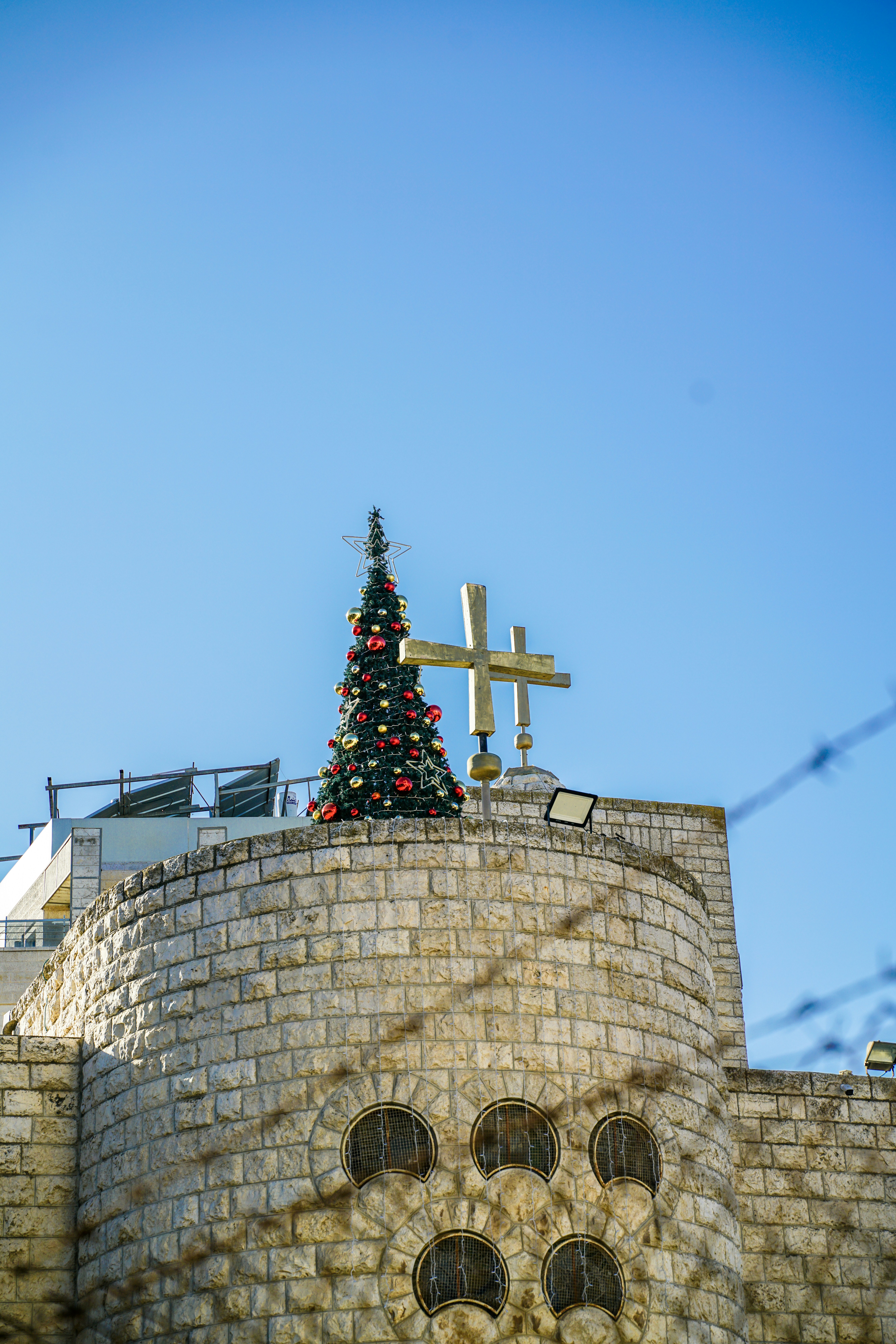 Decorated christmas tree on a stone building rooftop.