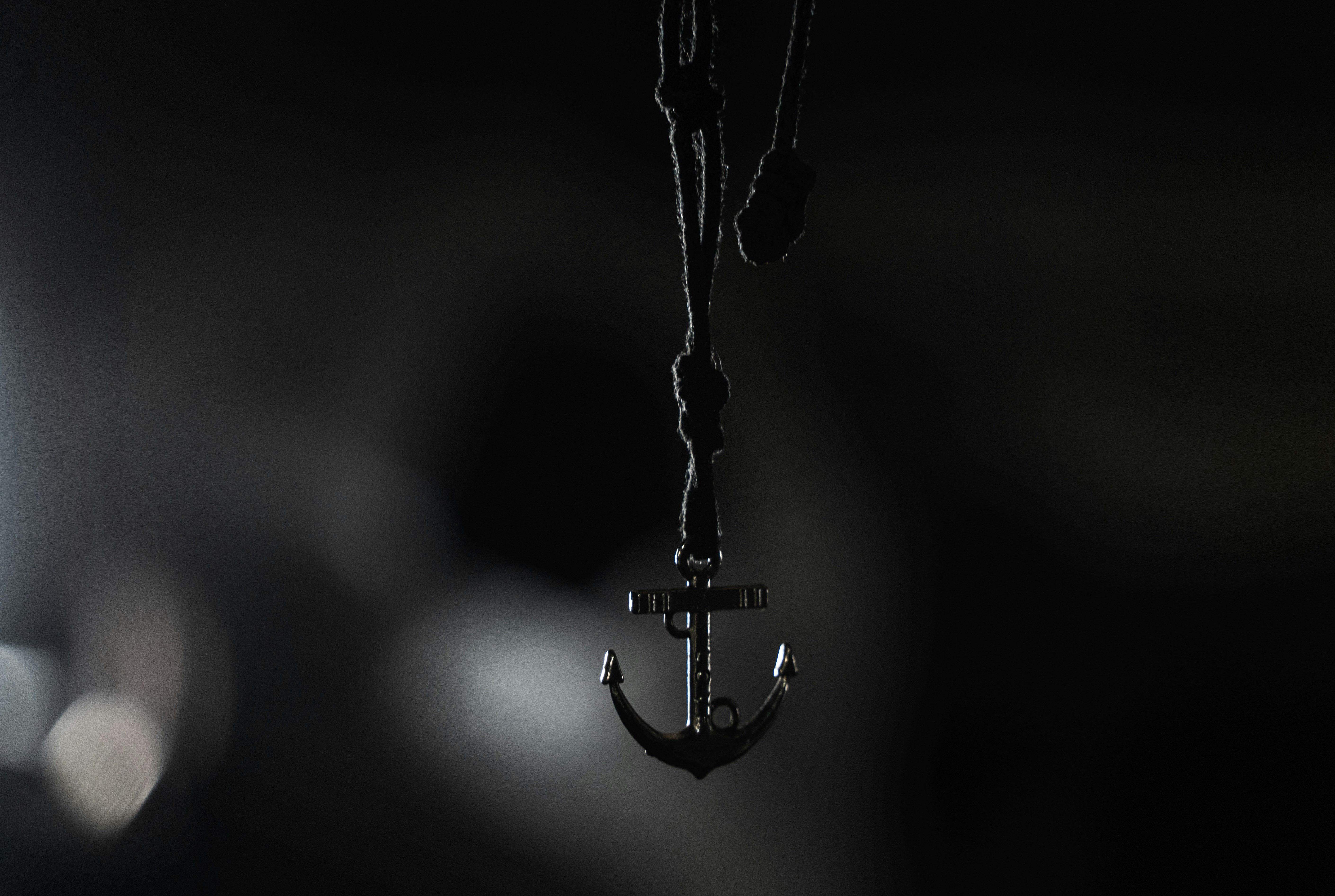 A small anchor pendant hangs from a dark cord.