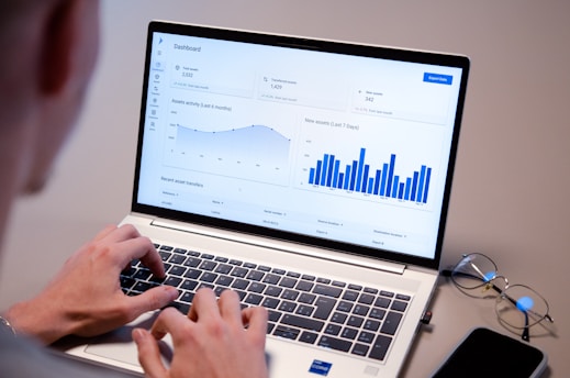 Person typing on laptop with data charts on screen