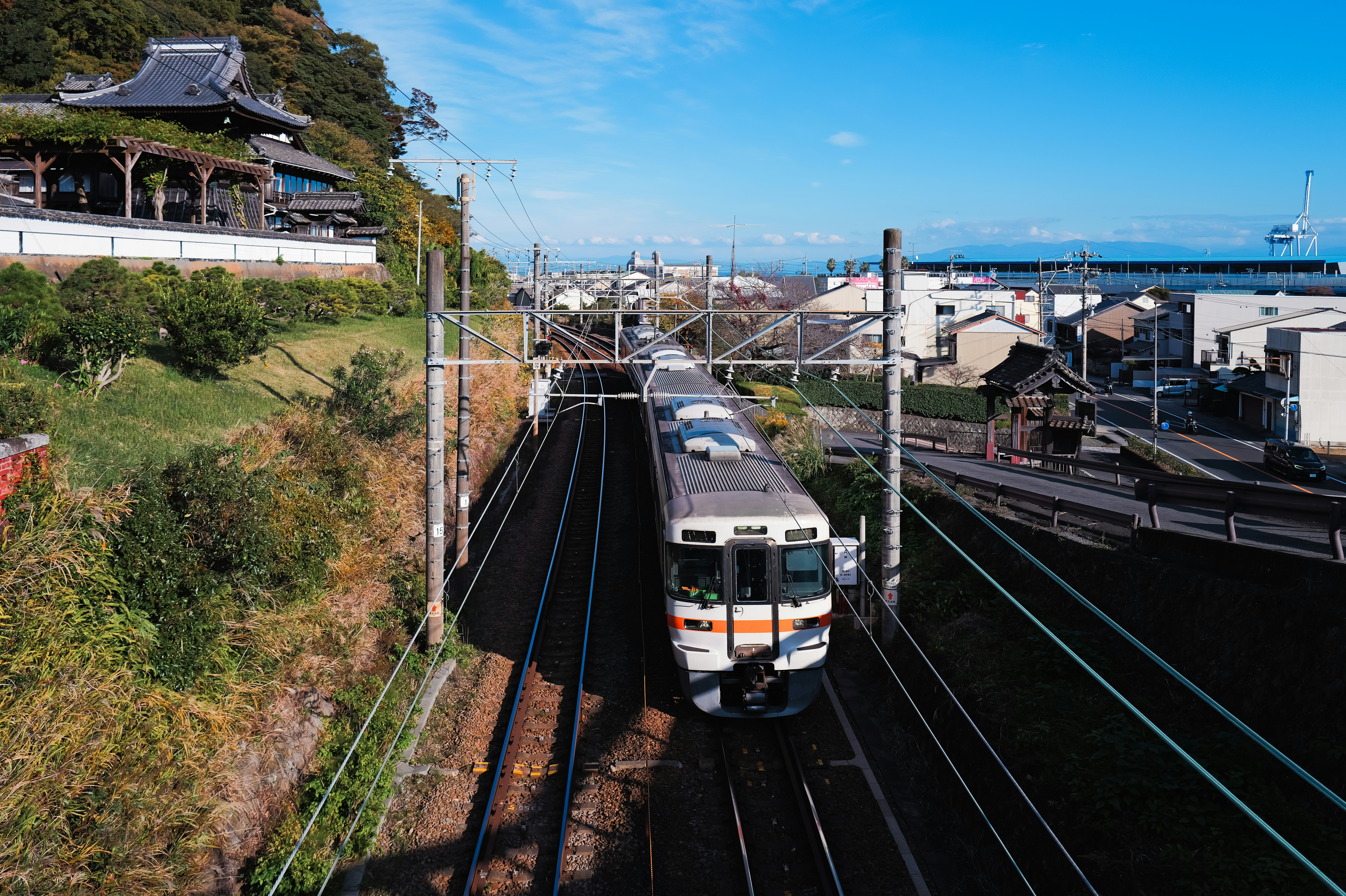 Train traveling on tracks through a japanese town.