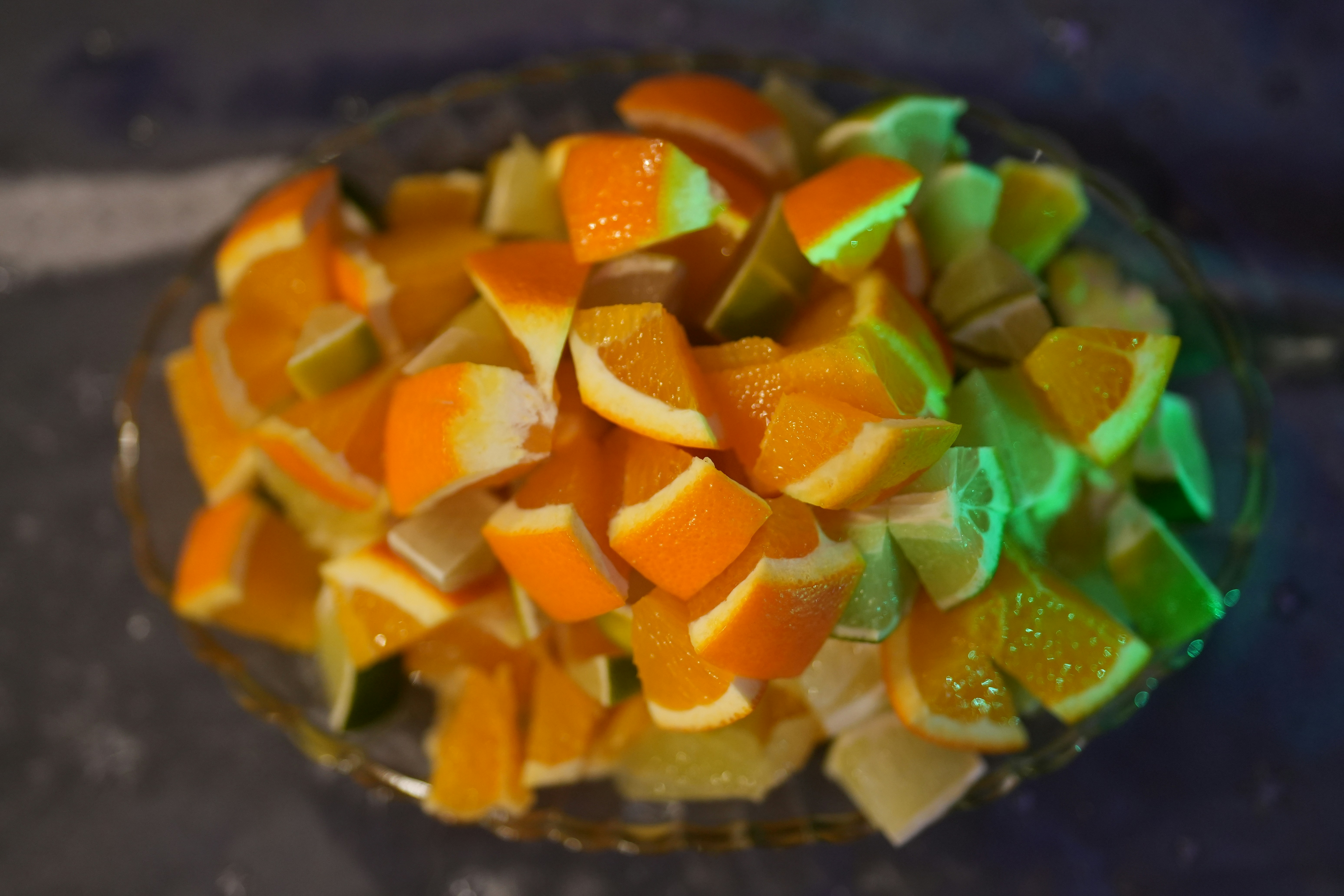 Sliced oranges and limes in a glass bowl.