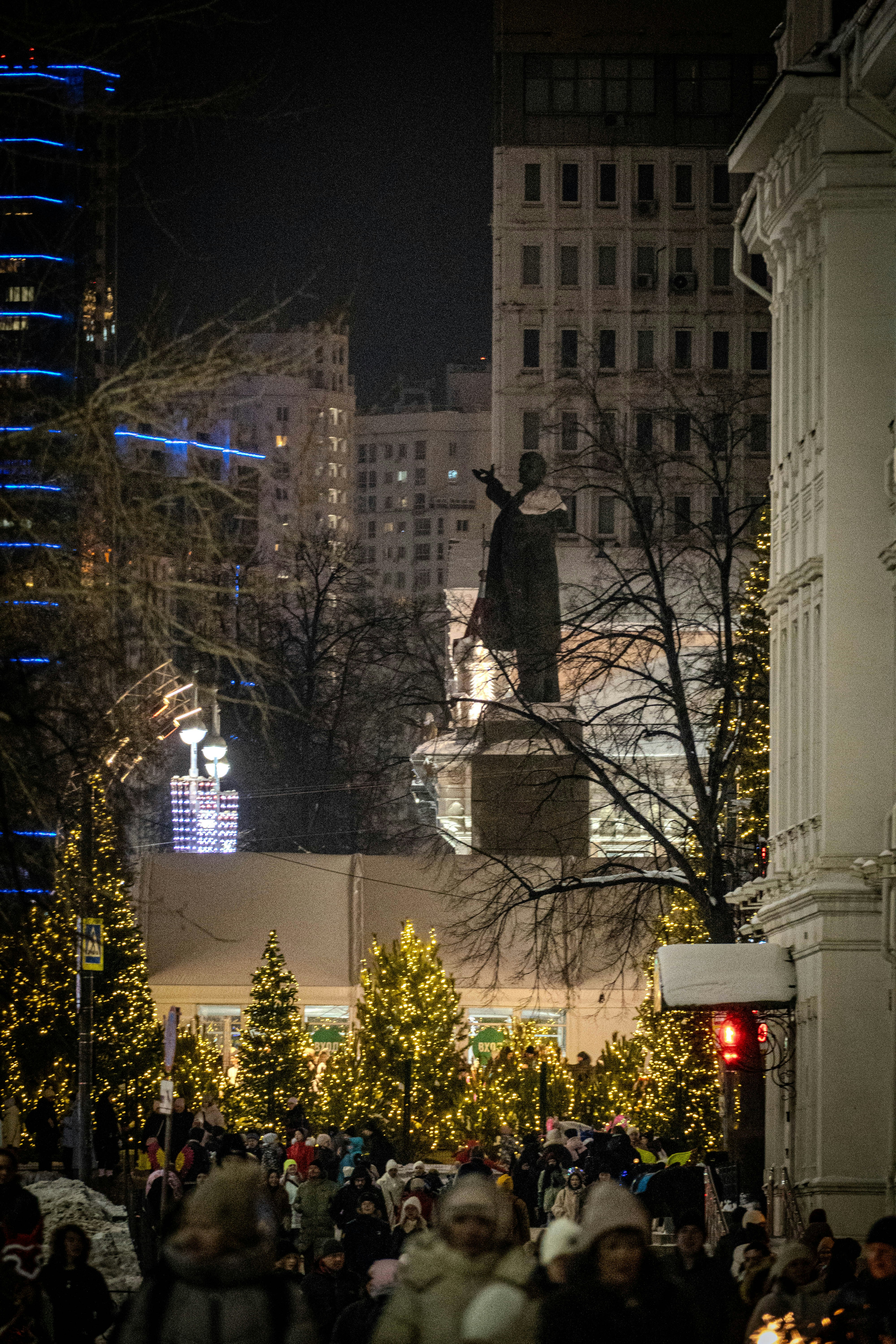 La gente camina por una calle festiva decorada con árboles de Navidad