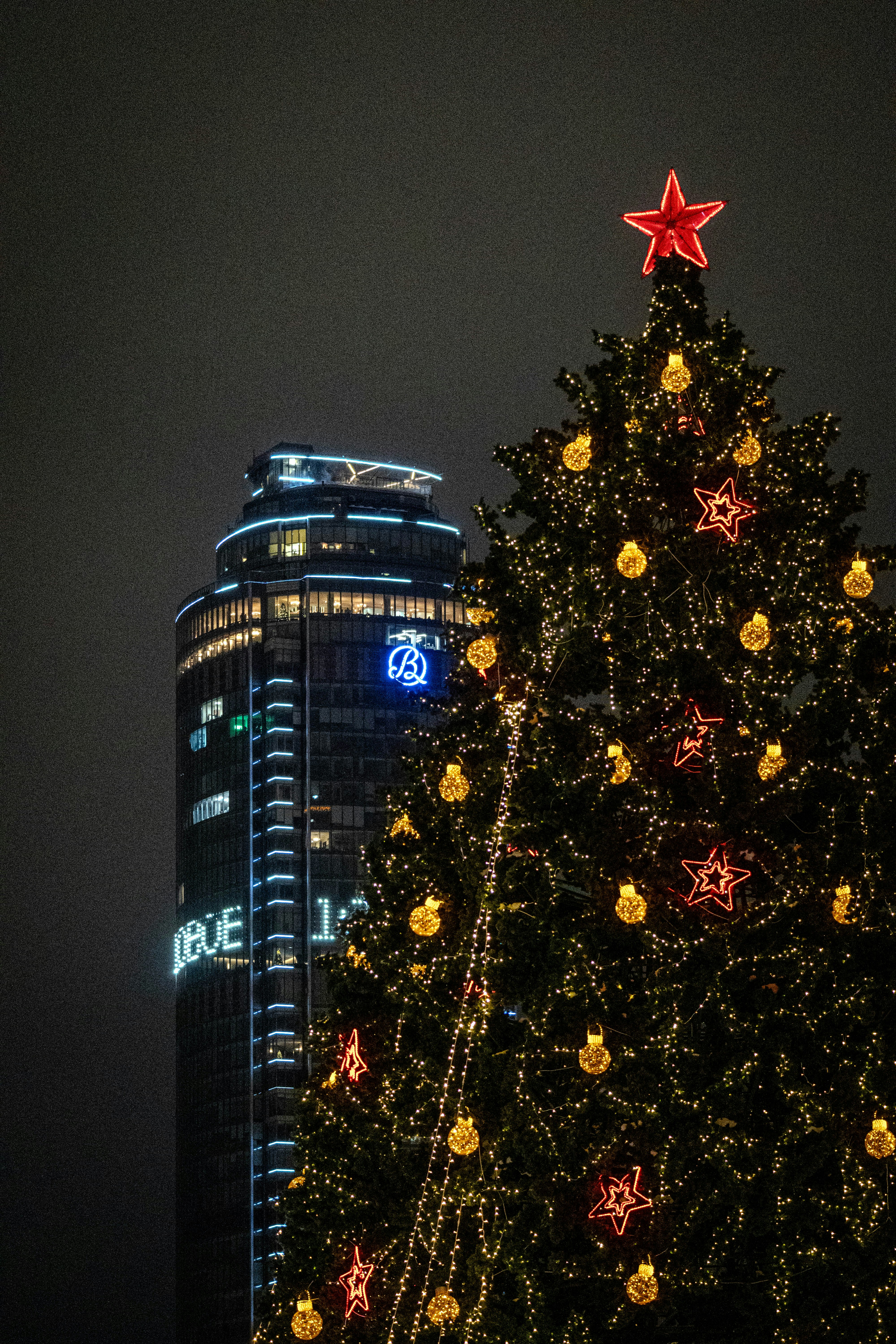 Un árbol de Navidad decorado delante de un rascacielos moderno.