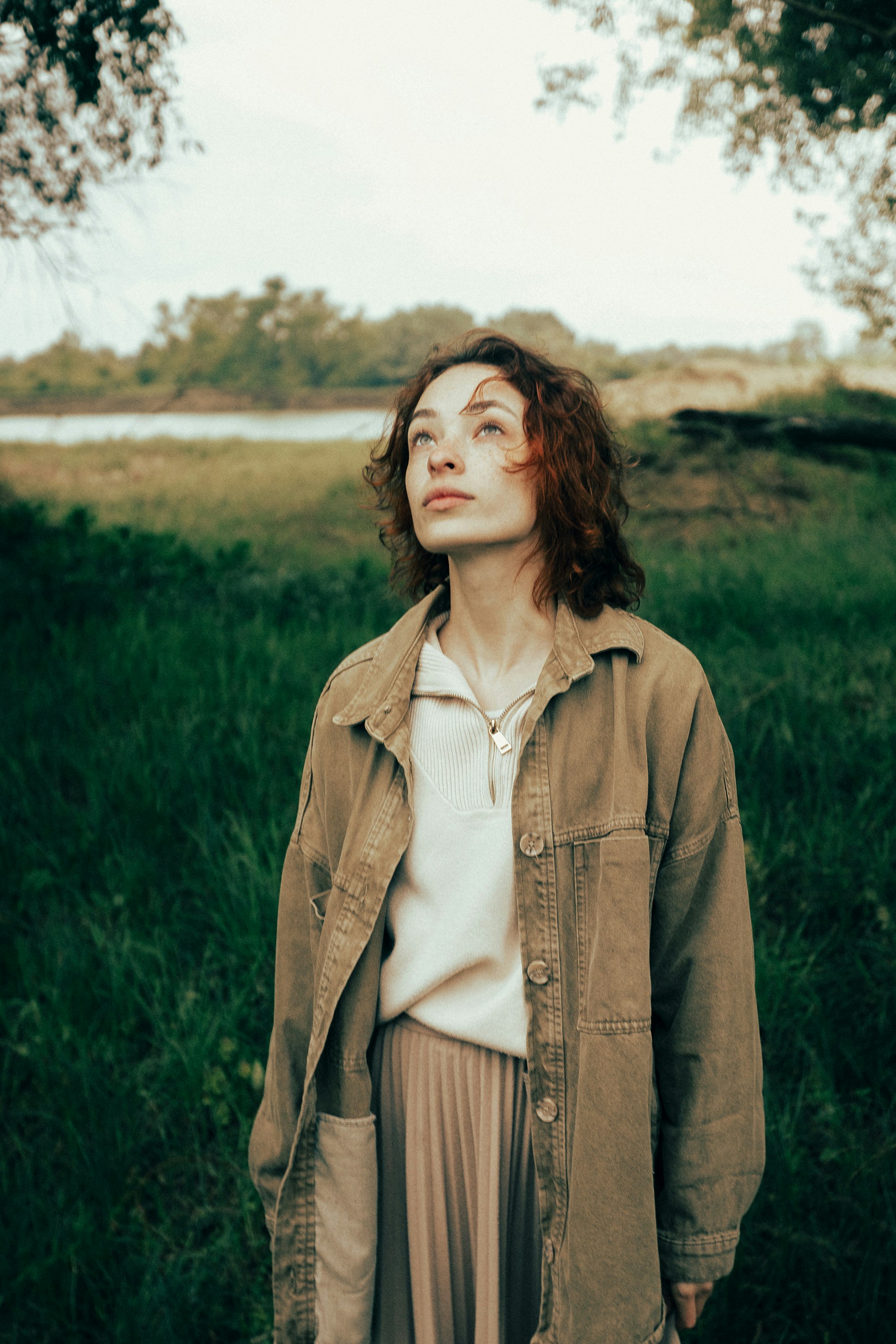 Young woman looking up in a grassy field