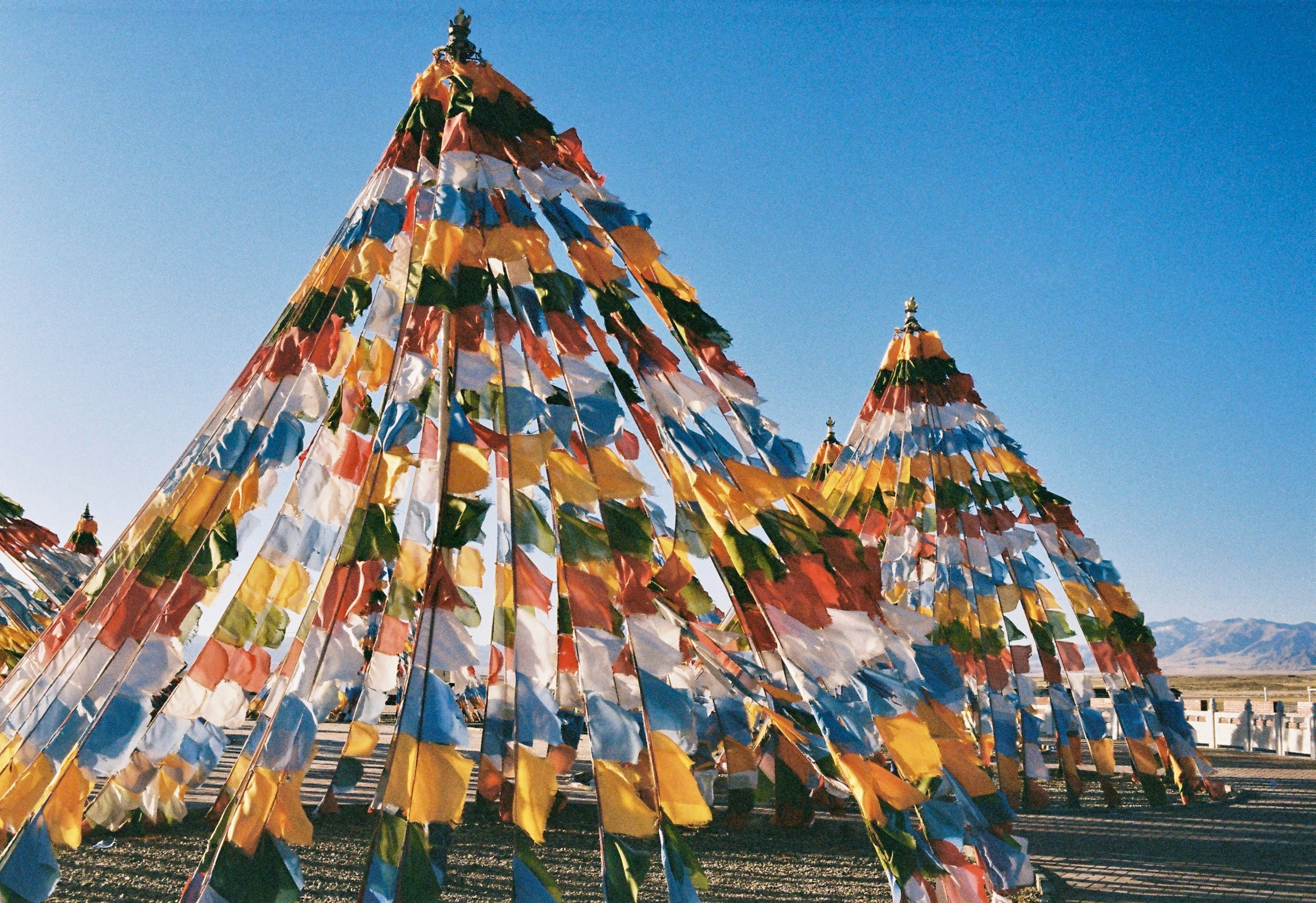 Colorful prayer flags adorning pyramid structures under a clear sky.