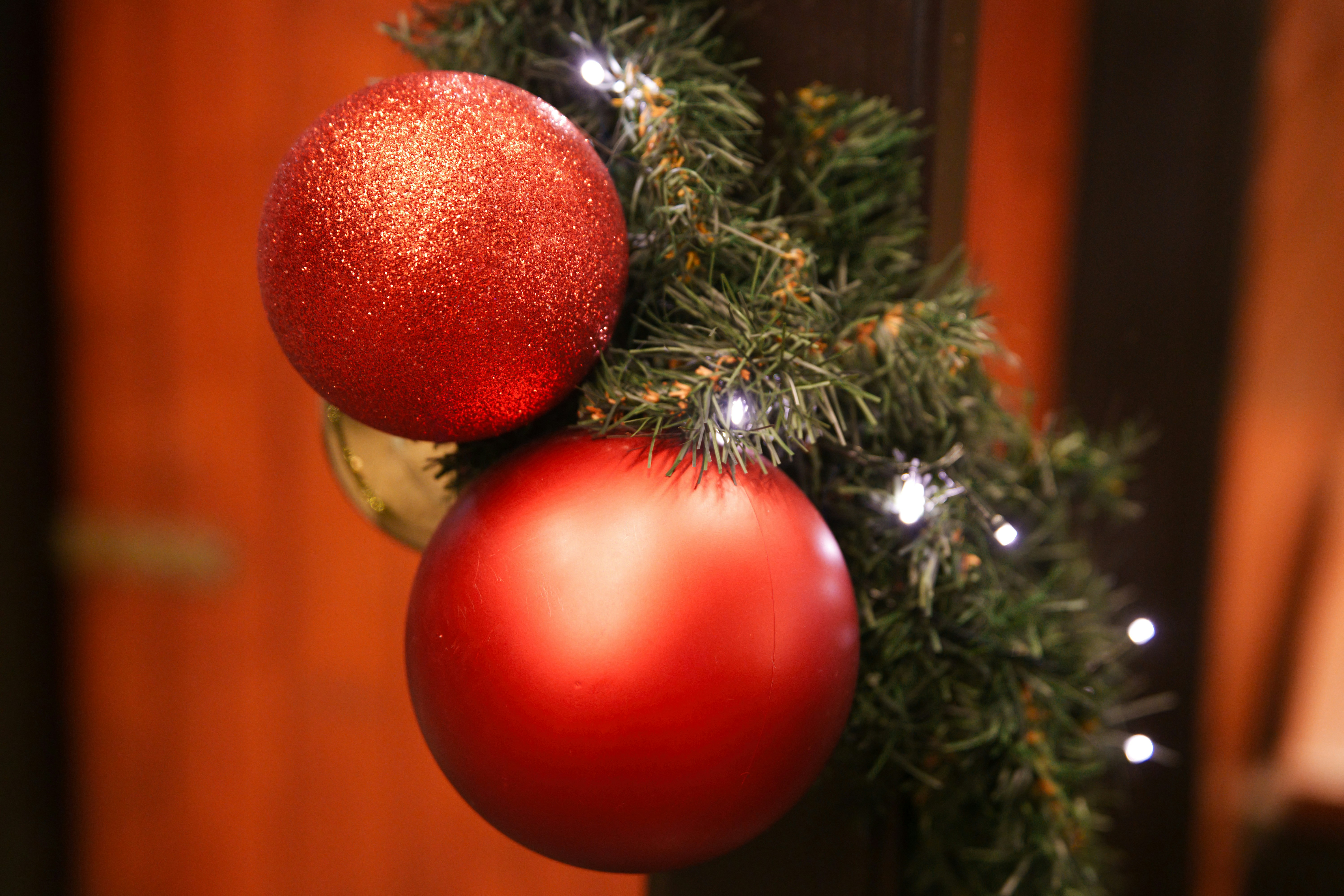 Red christmas ornaments on evergreen garland with lights