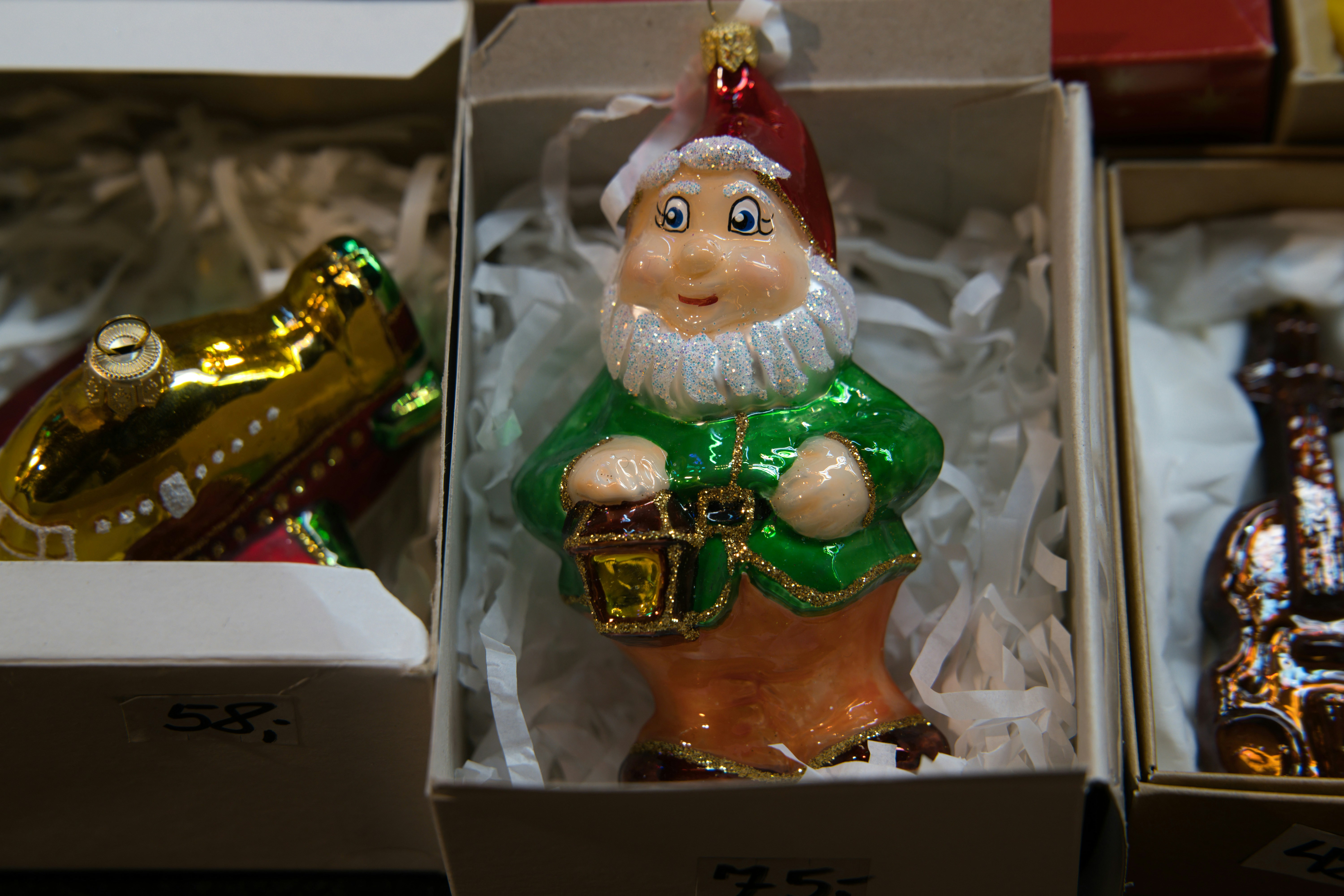 A gnome ornament holding a lantern in a box.