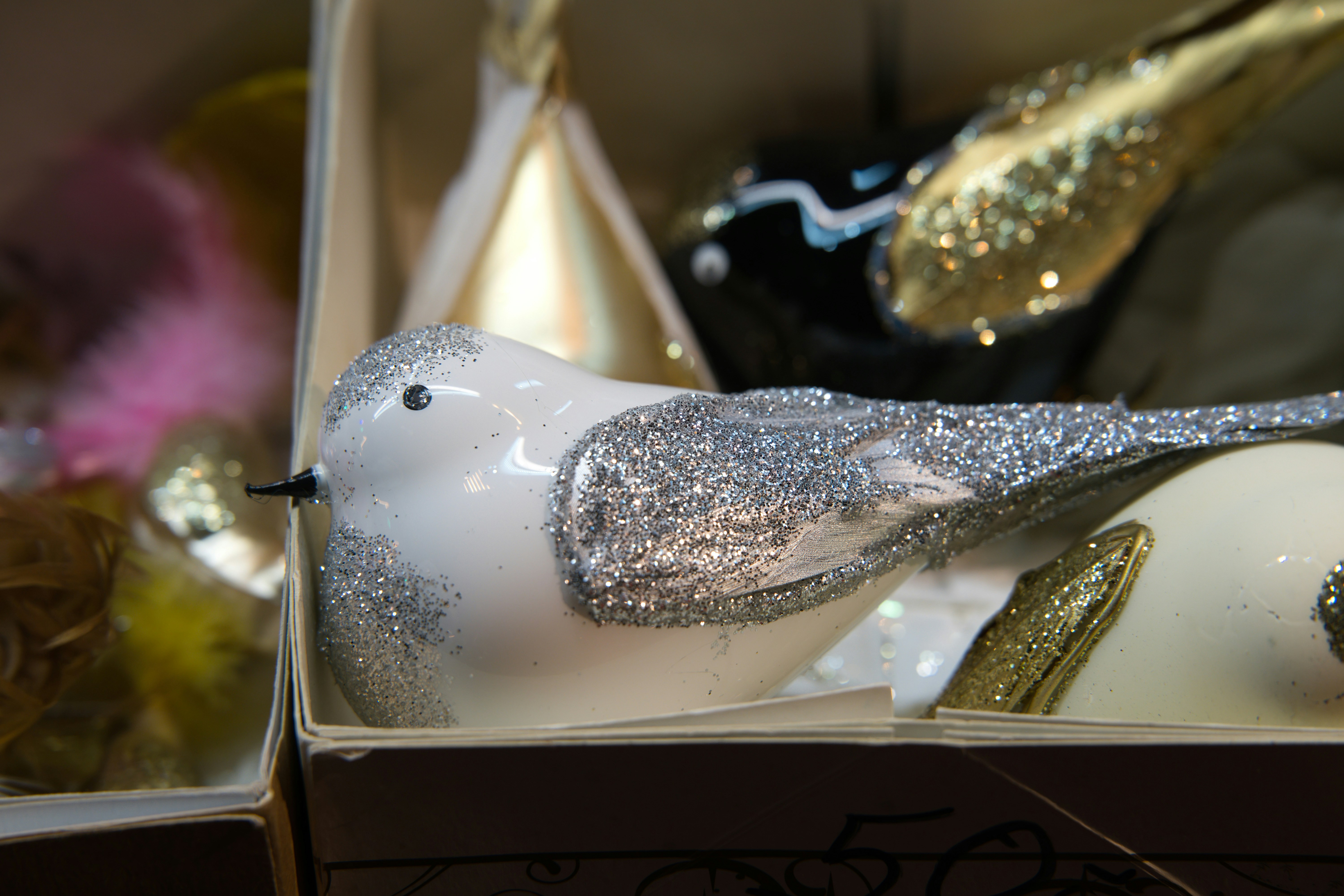 A white glittery bird ornament in a box.