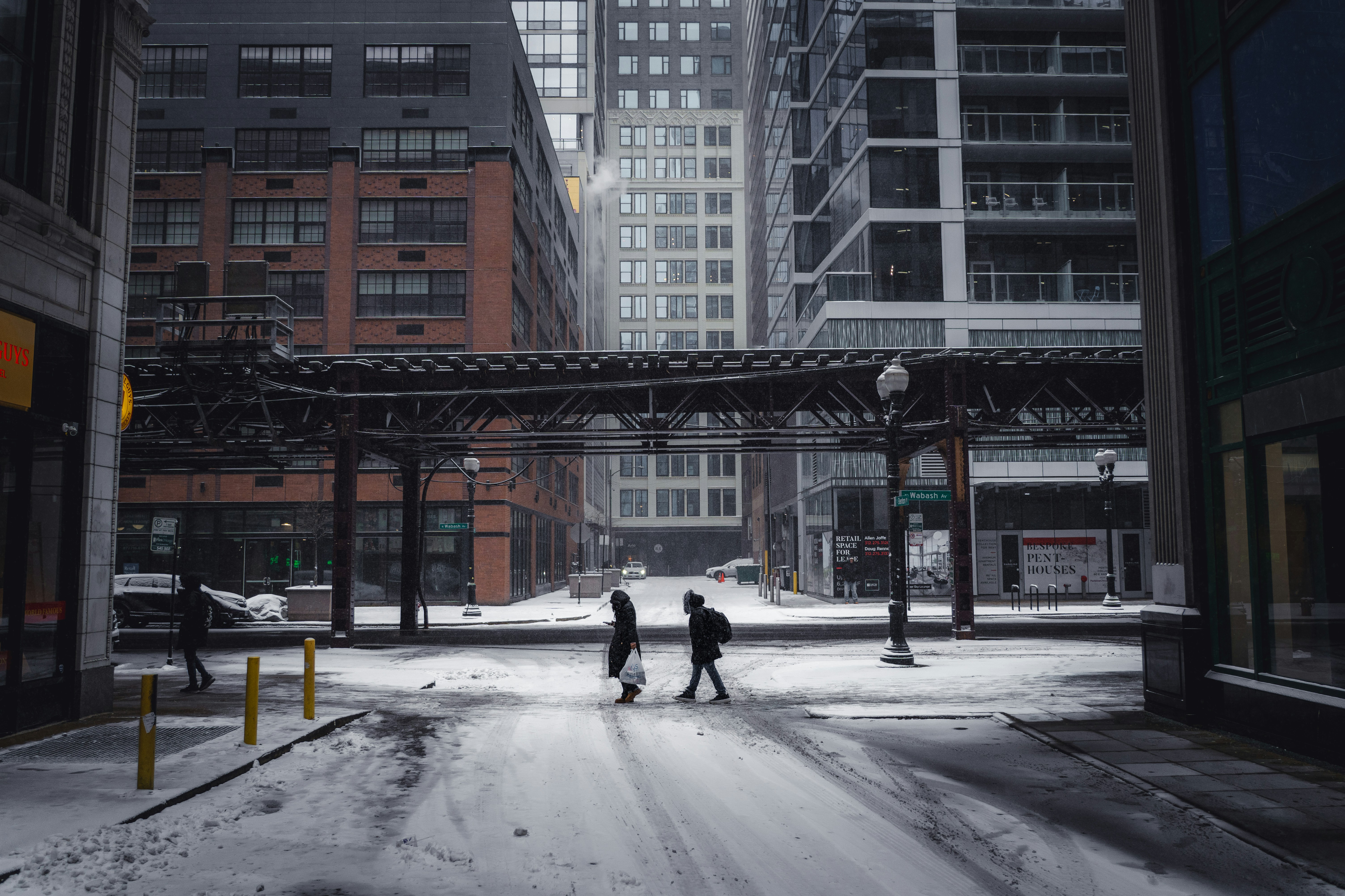 Menschen überqueren eine verschneite Straße in einer Stadt.