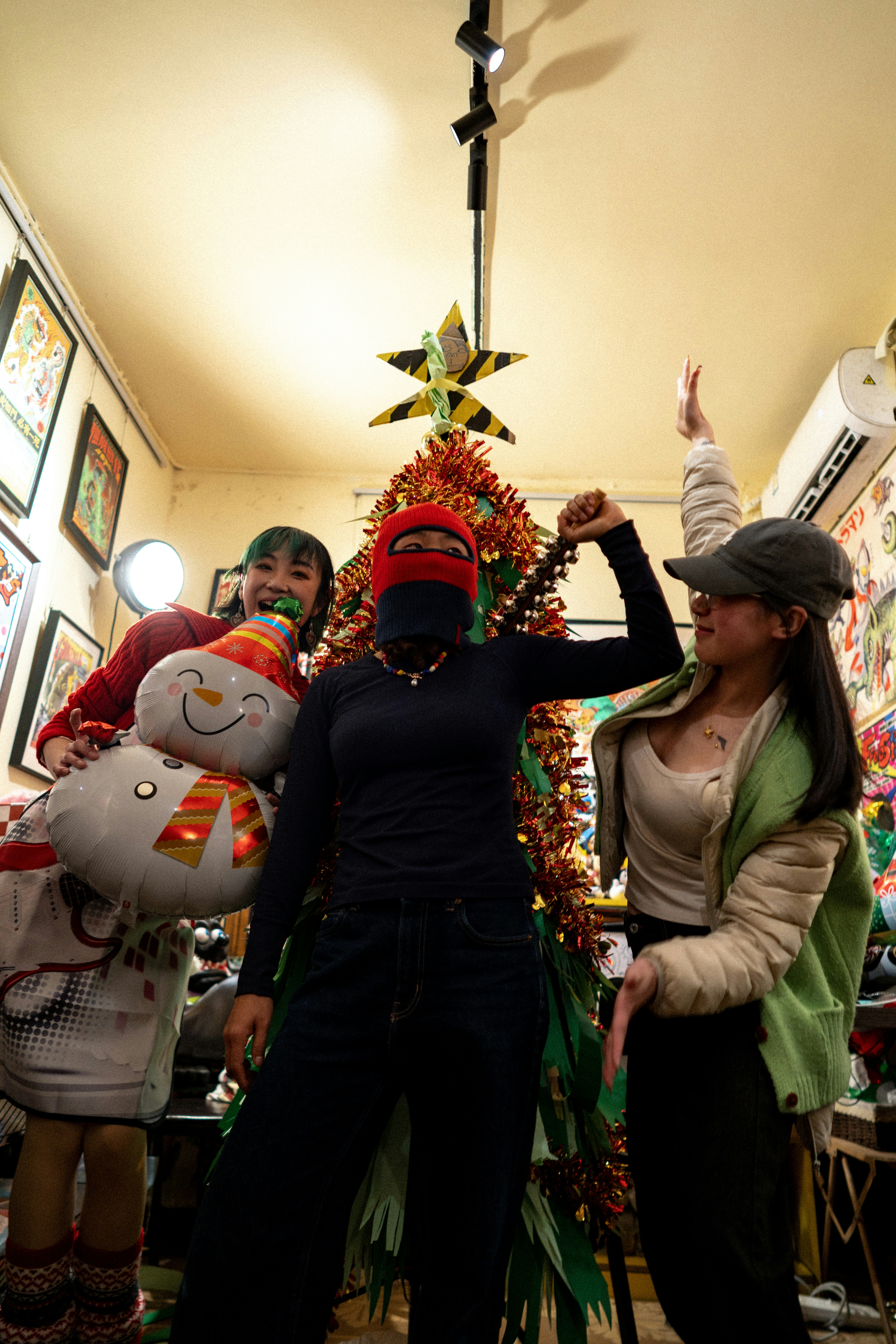 Three friends posing with a christmas tree and snowman.