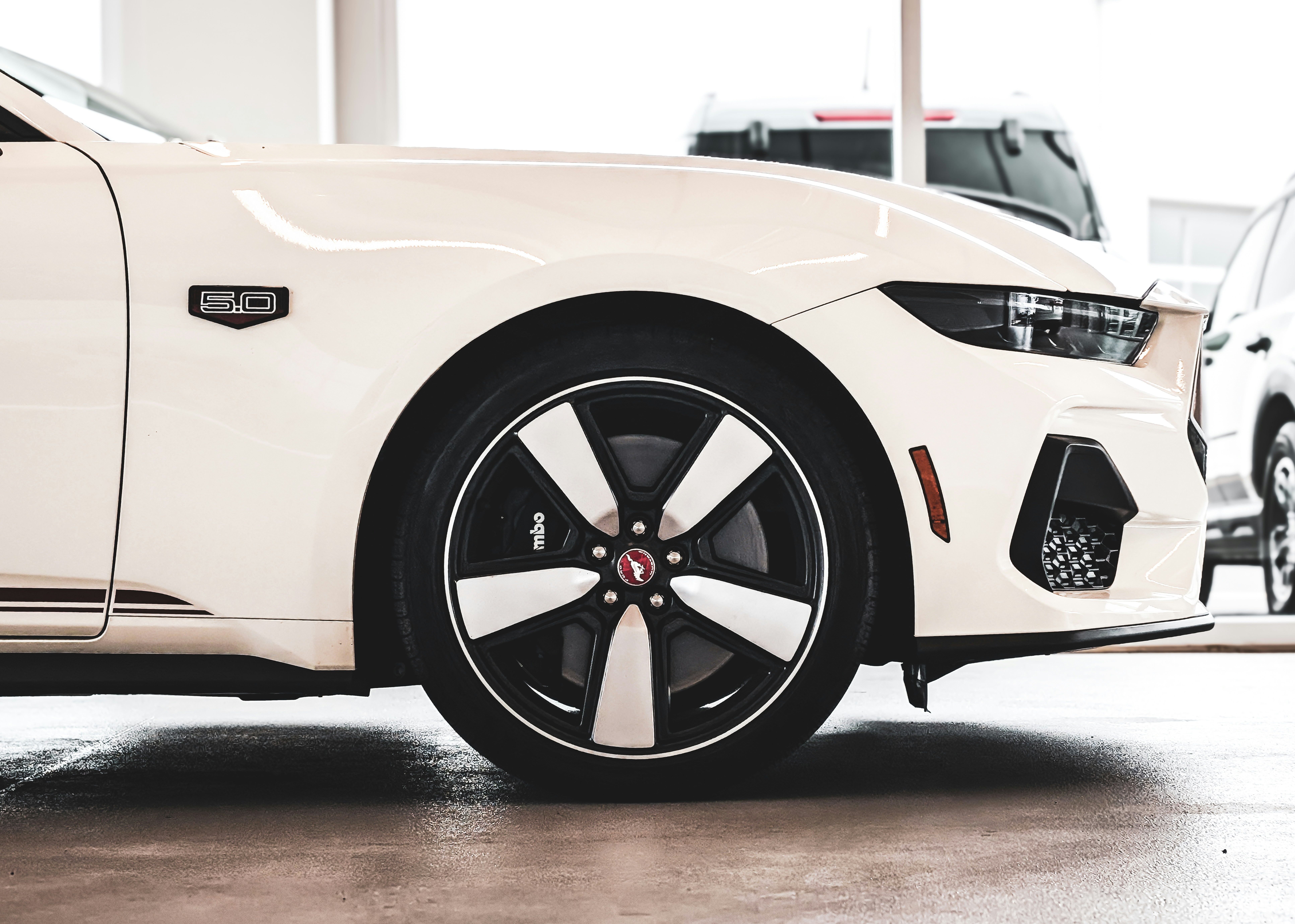 White sports car with black and white wheel.